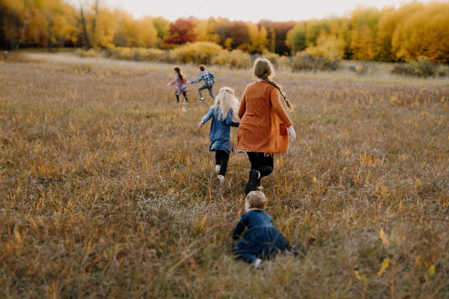 Siblings run through a fall field