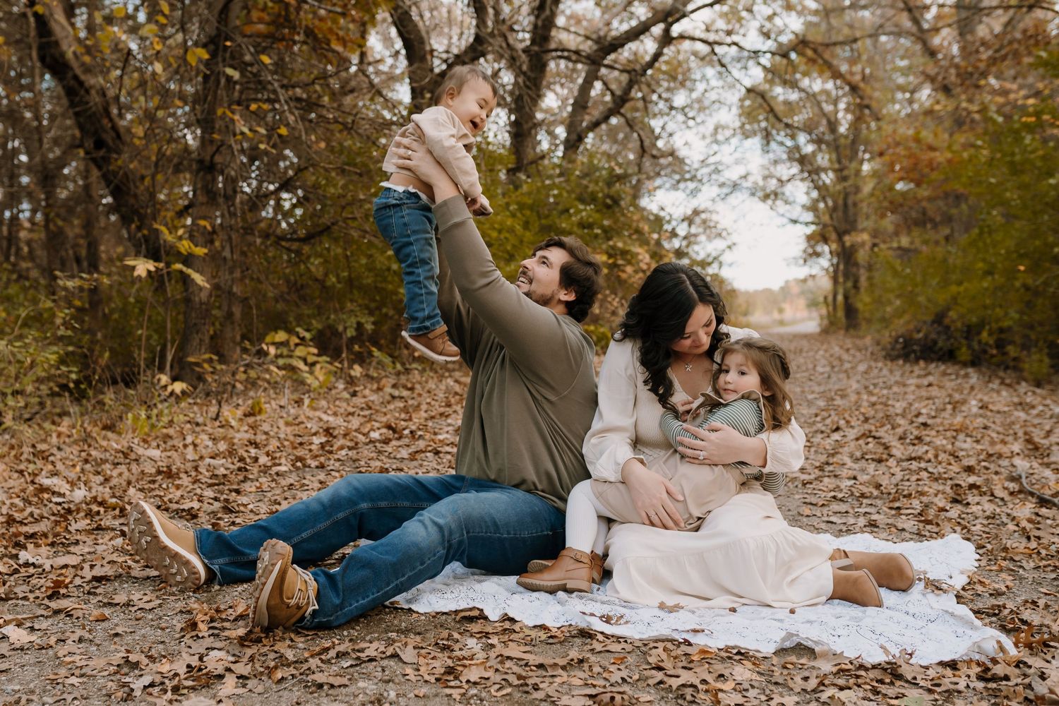family sitting on a path during fall family photoshoot with minnesota photographer