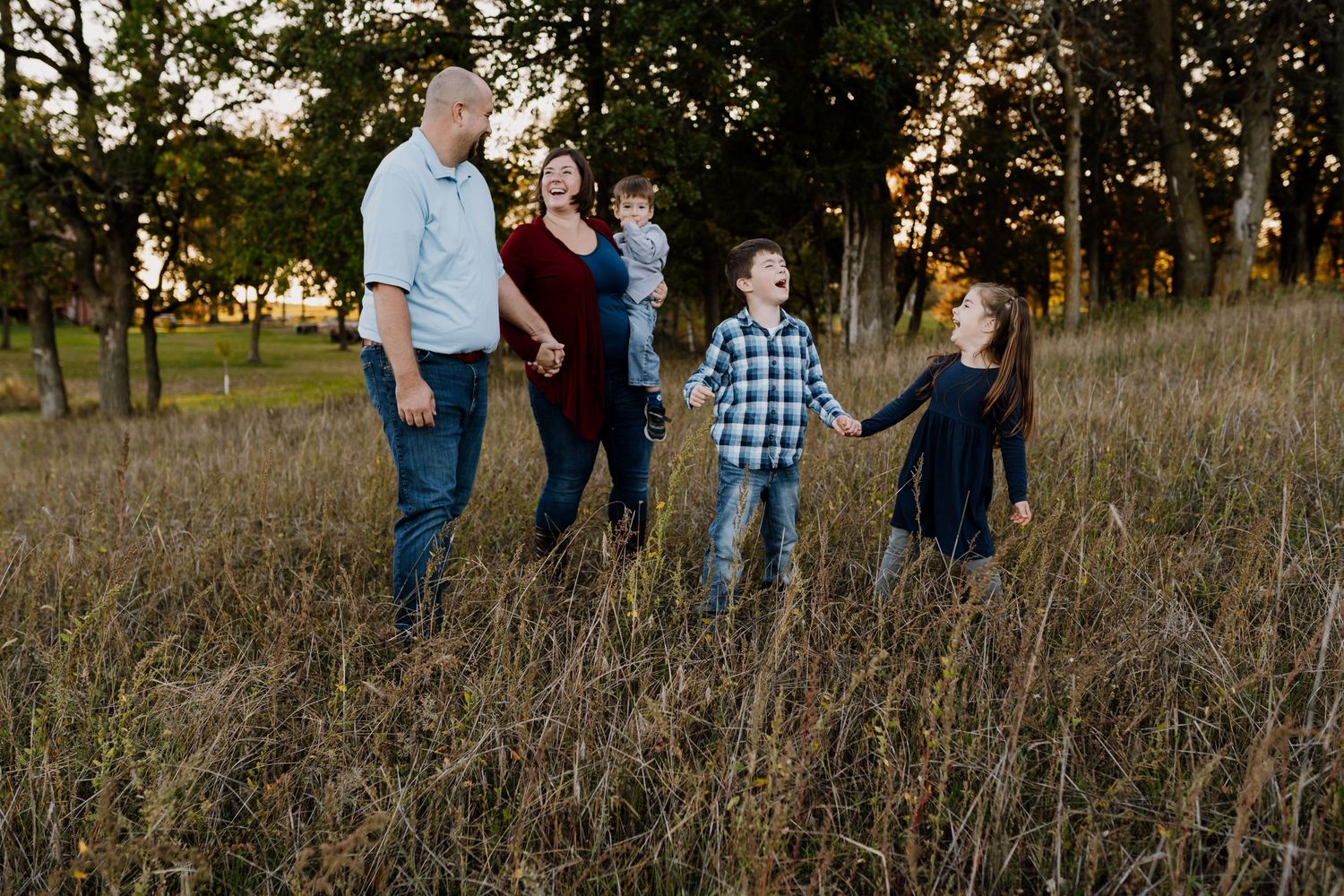 Family walks through field during outdoor family photography session