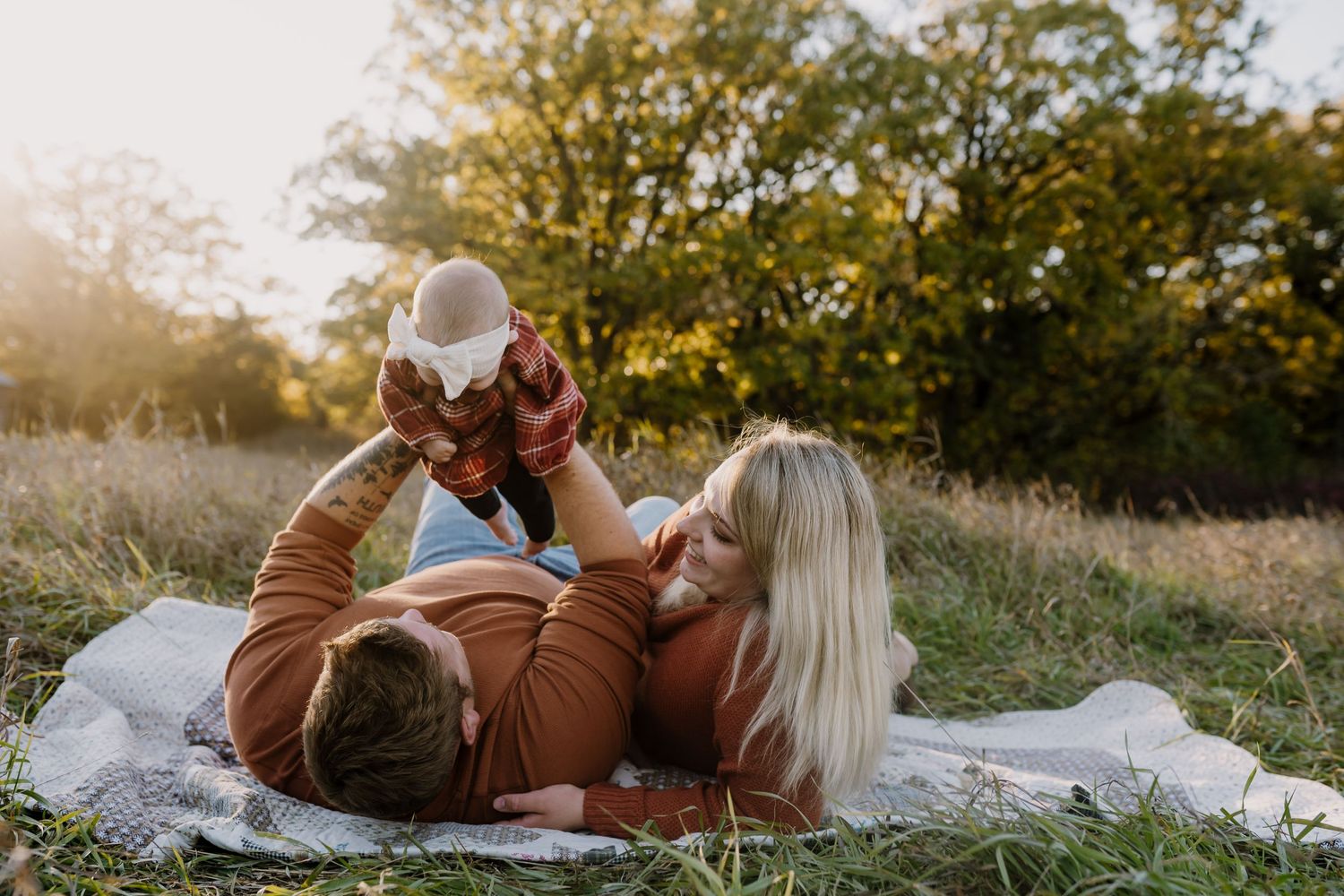 mom and dad laying on blanket playing with baby during family pictures with minnesota photographer
