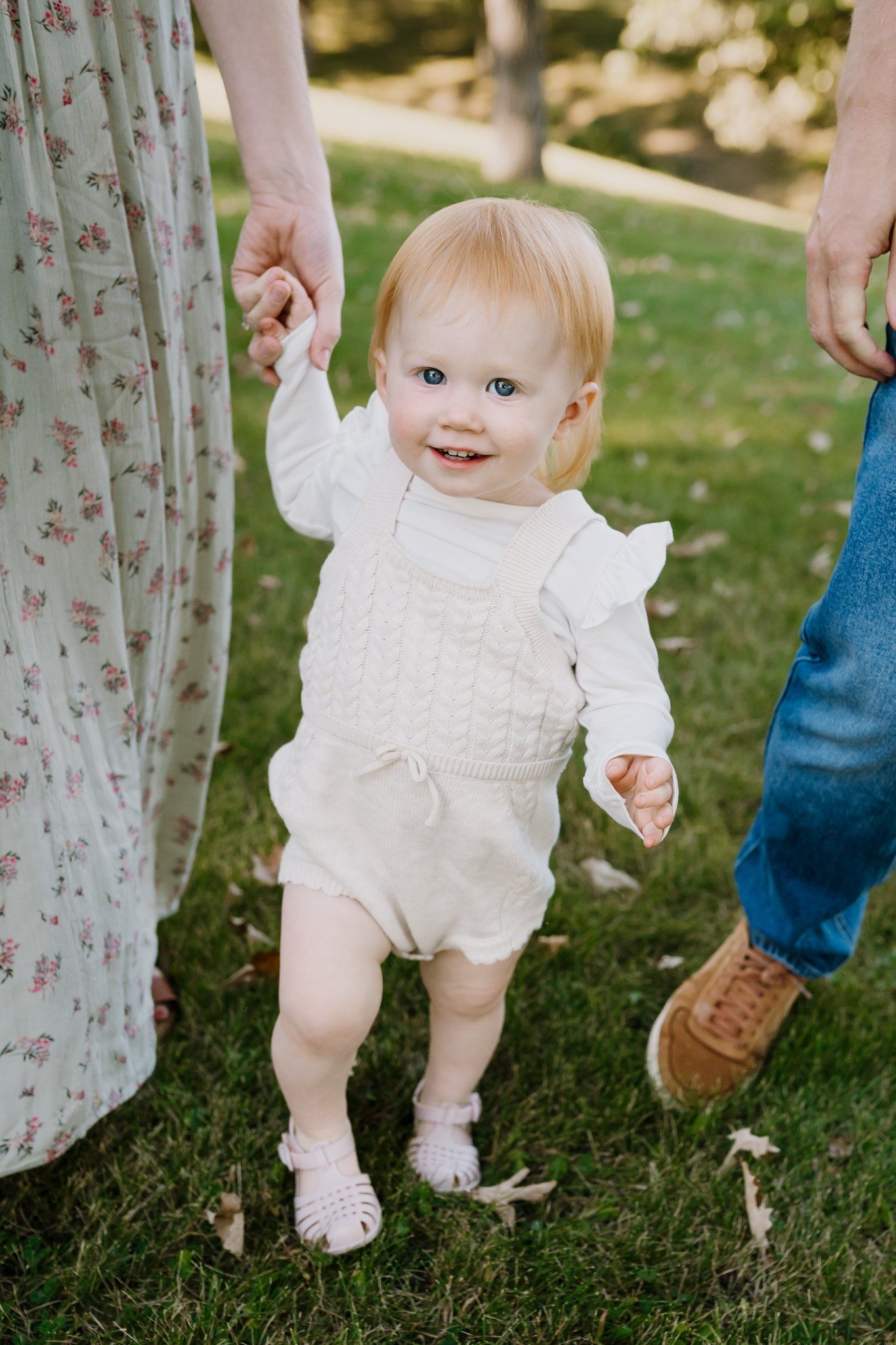 Little girl holding mother's hand smiles