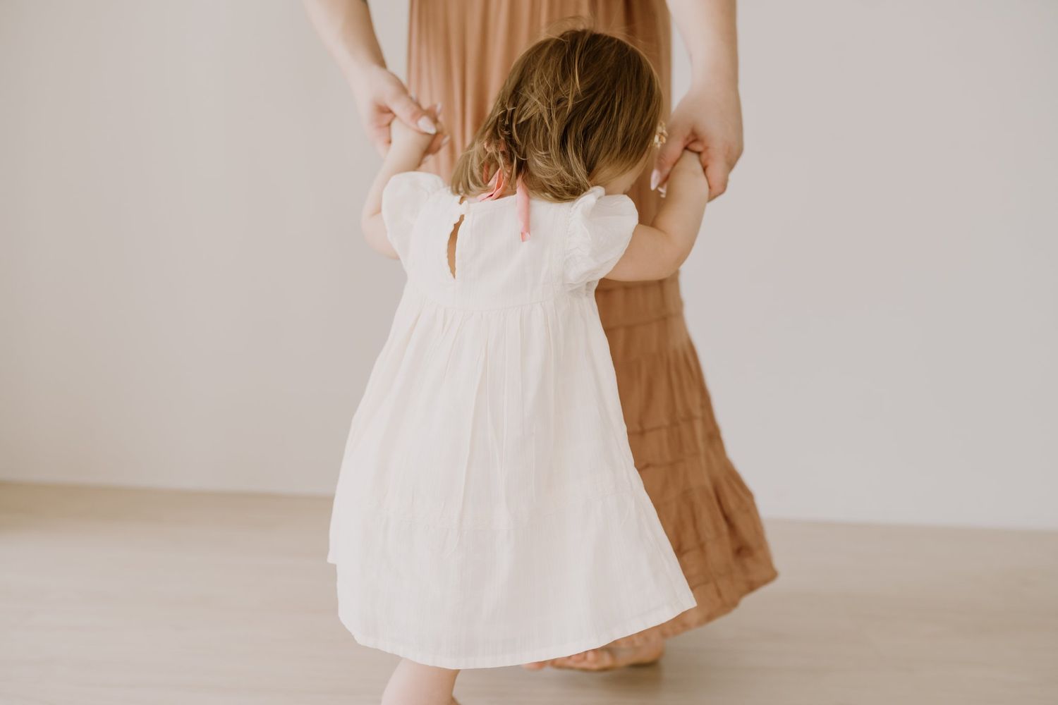 Mom dances with her toddler daughter in a photography studiio