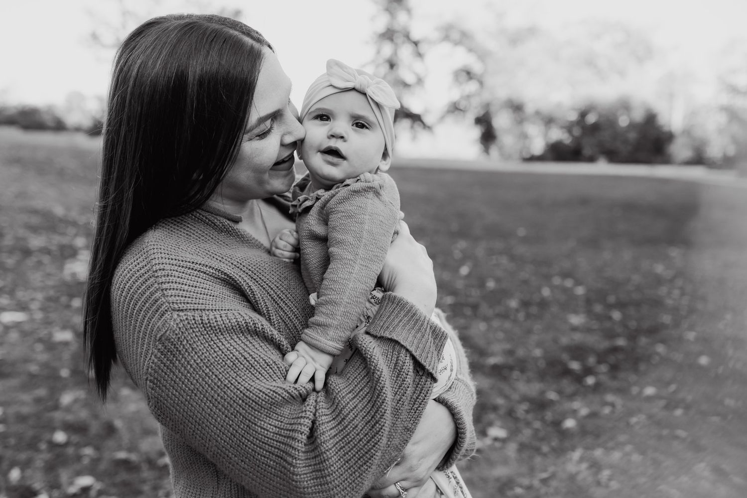 Mom kisses baby girl while standing outside