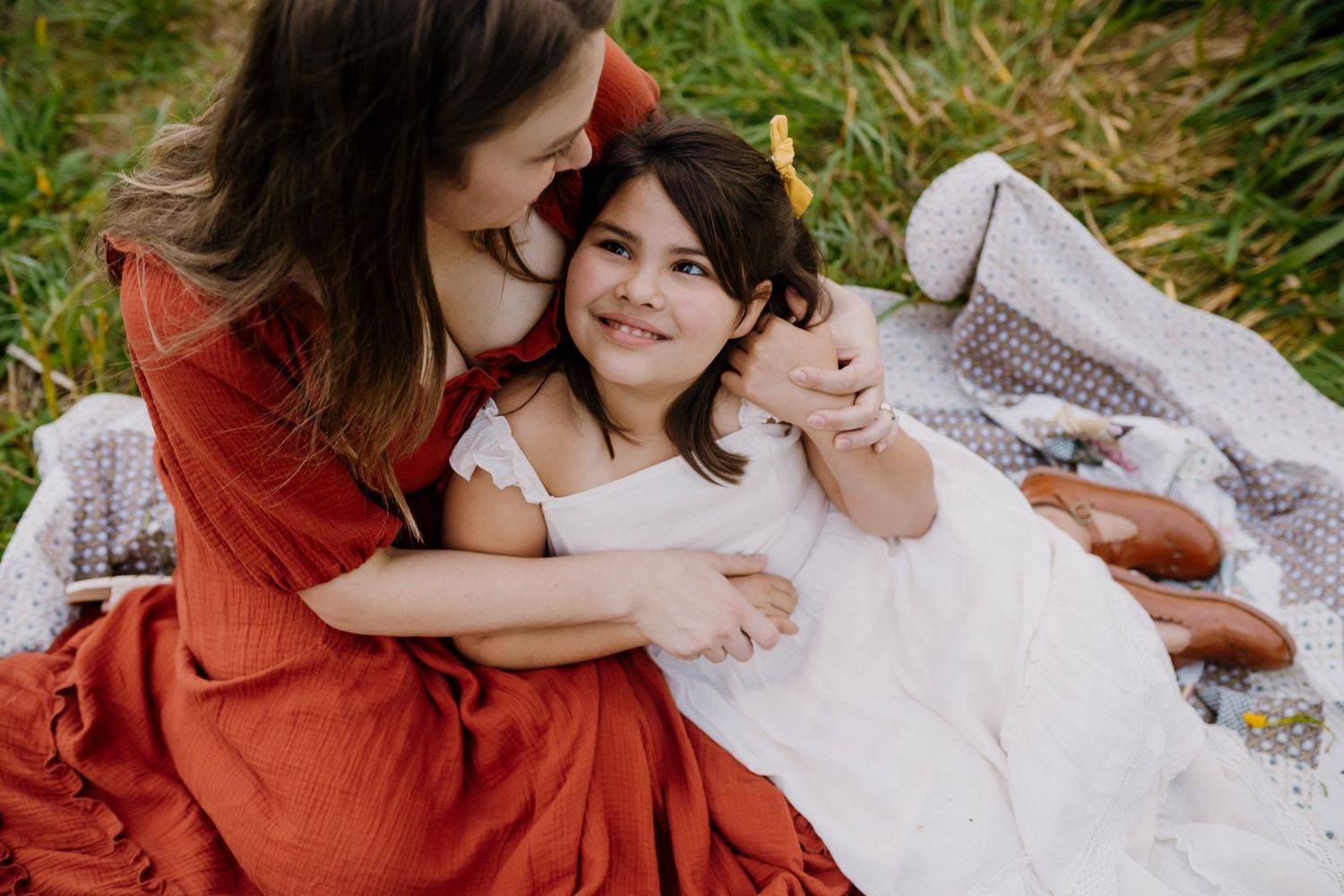 Little girl looks up at her mom and smiles during family photos