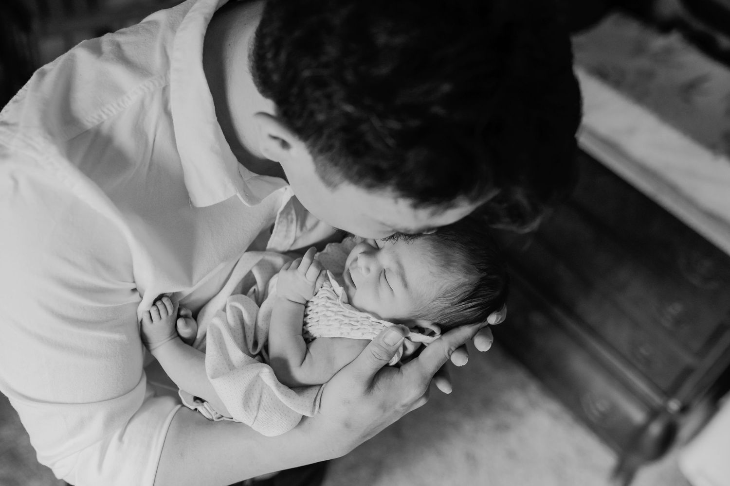 Man holds newborn and kisses her head