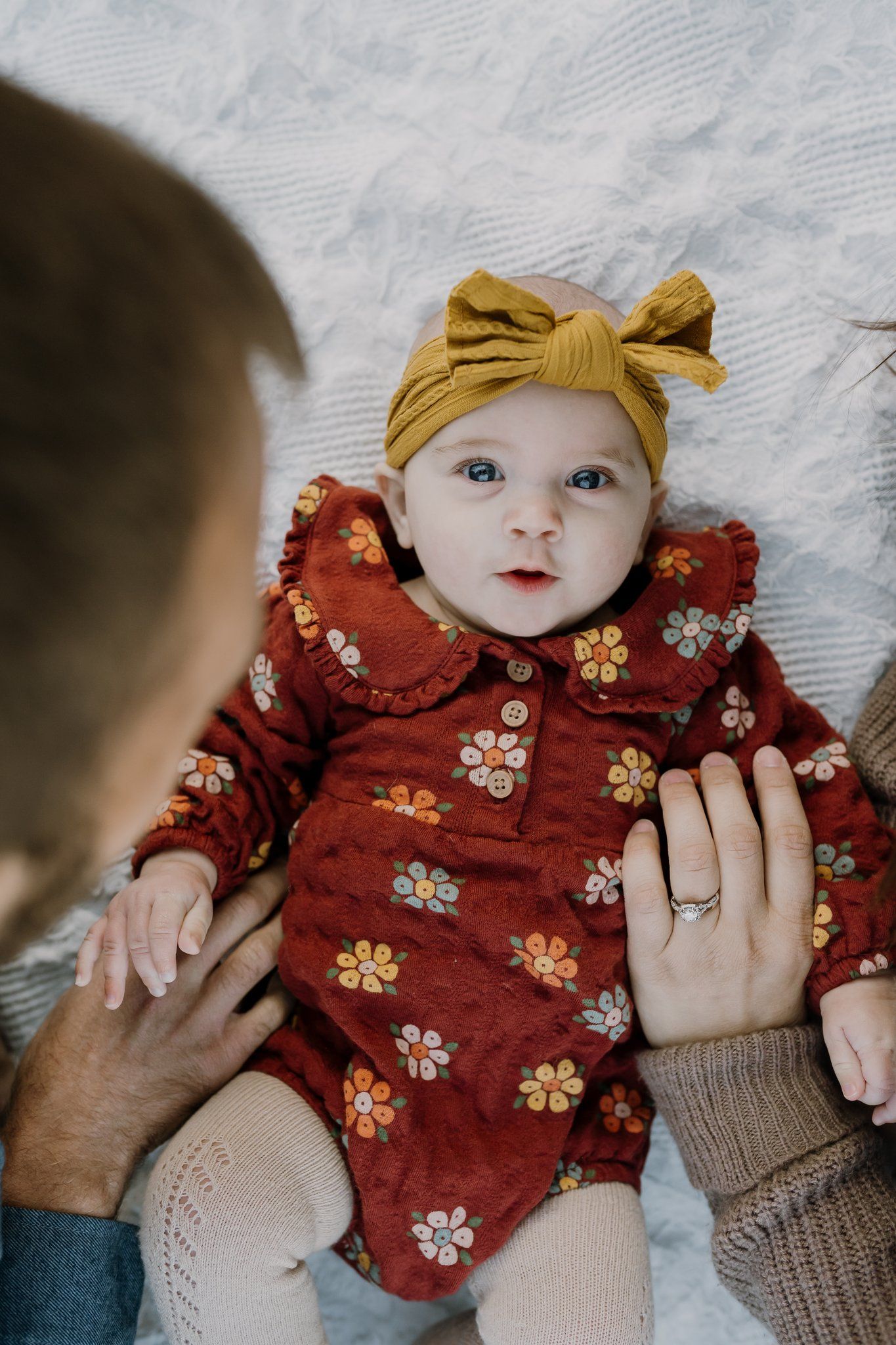 Baby girl looks at Sony camera while dad and mom play with her