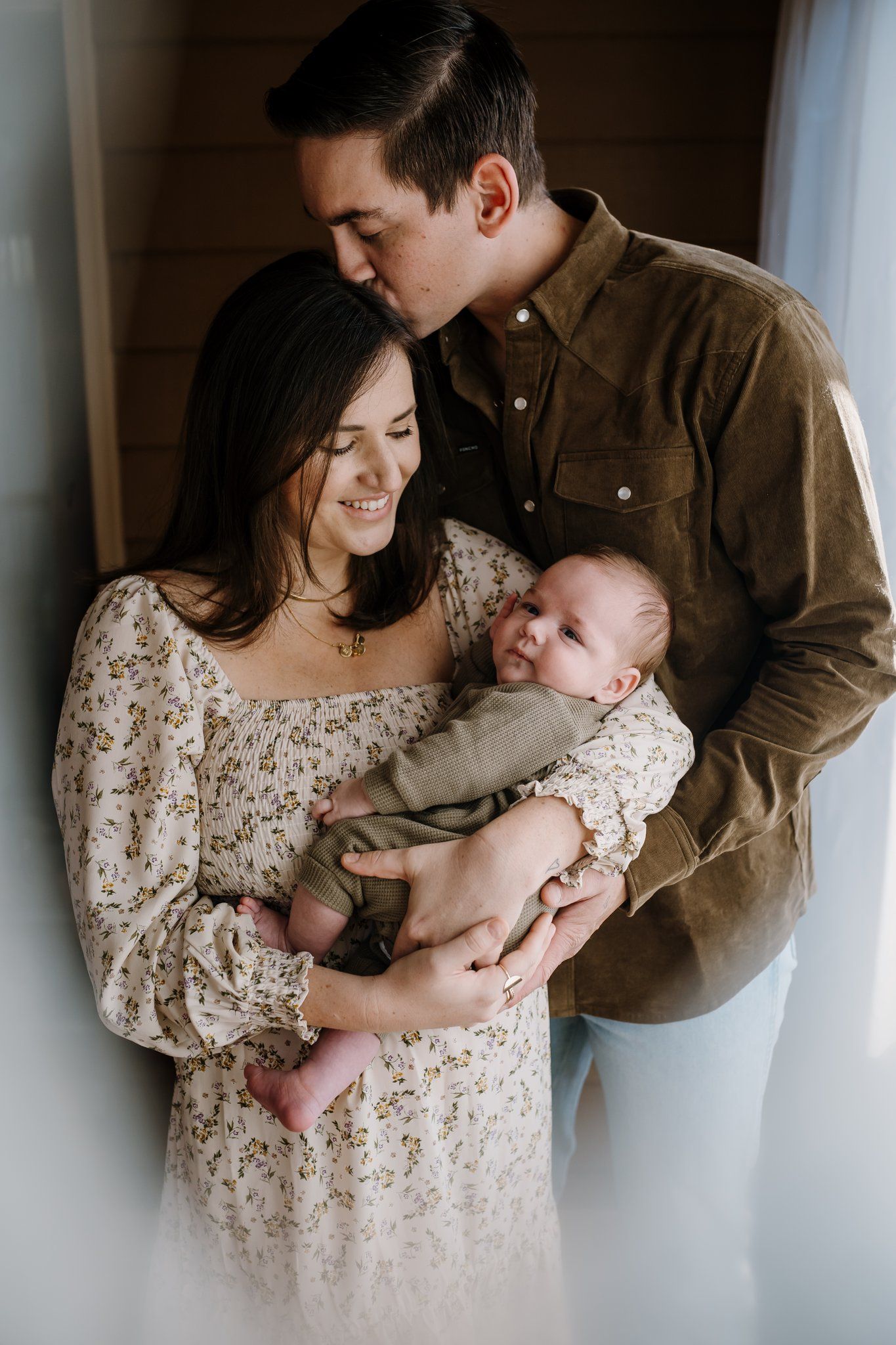 Parents embrace while holding baby