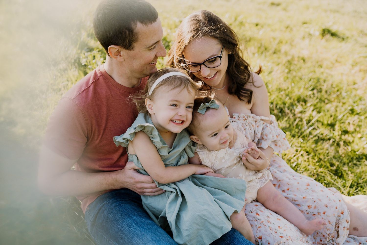 Parents snuggle with laughing toddler and baby