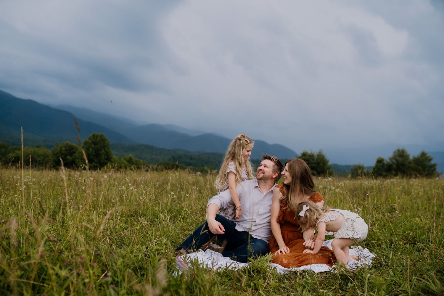Family snuggles and laughs on blanket during family photos in Cades Cove