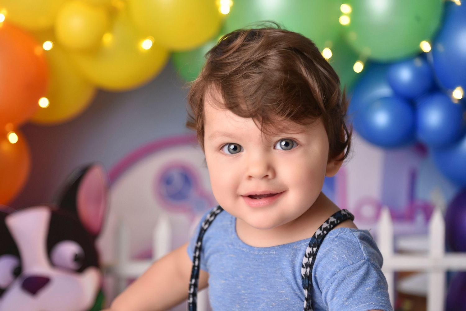 Colorful rainbow balloon backdrop with festive party lighting and decorations.