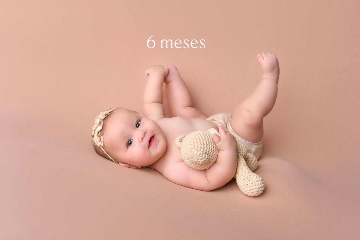 Newborn baby lies peacefully on pink backdrop with white seashells in artistic studio portrait.