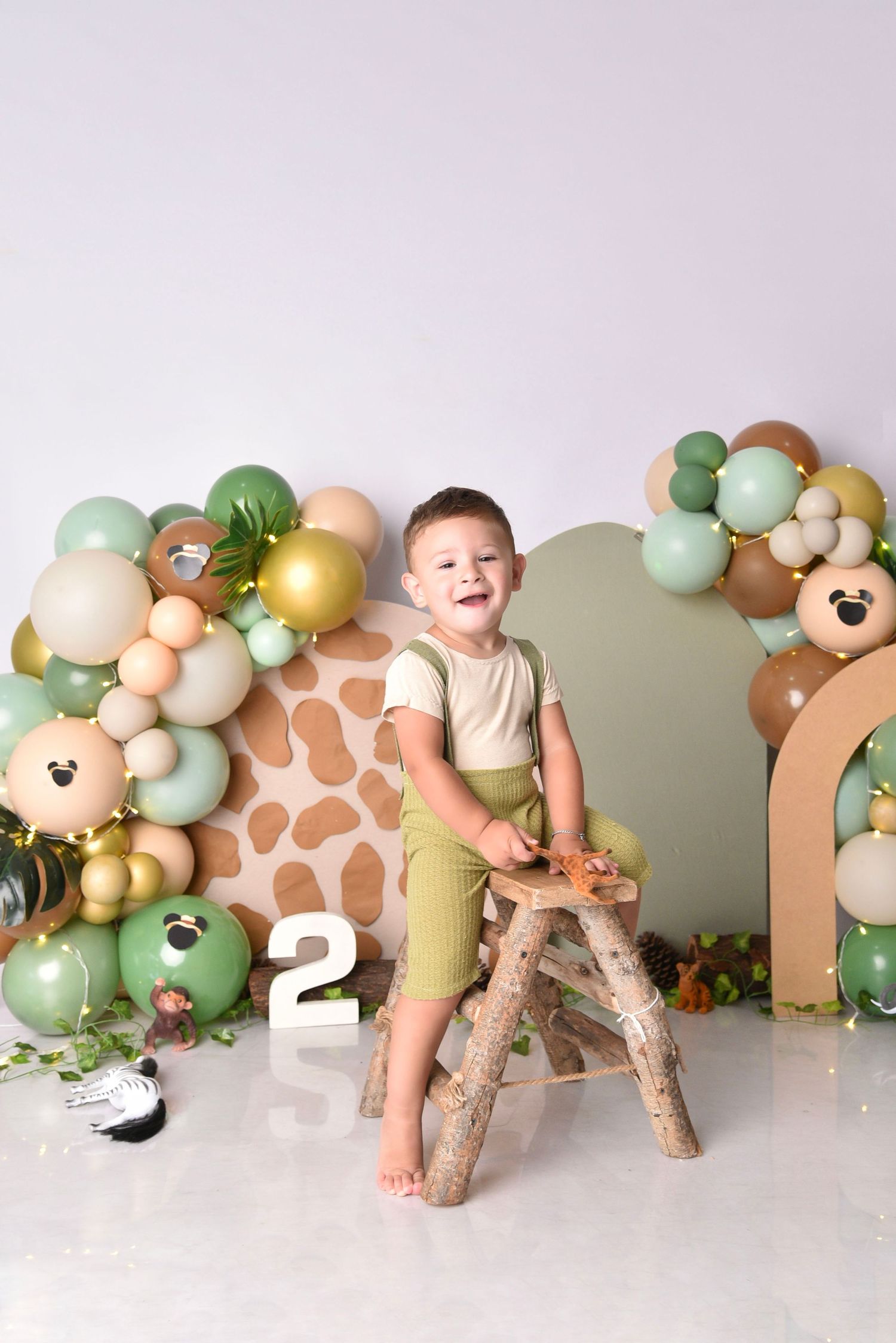 Safari themed birthday setup with mint green balloons and giraffe plush decorations.