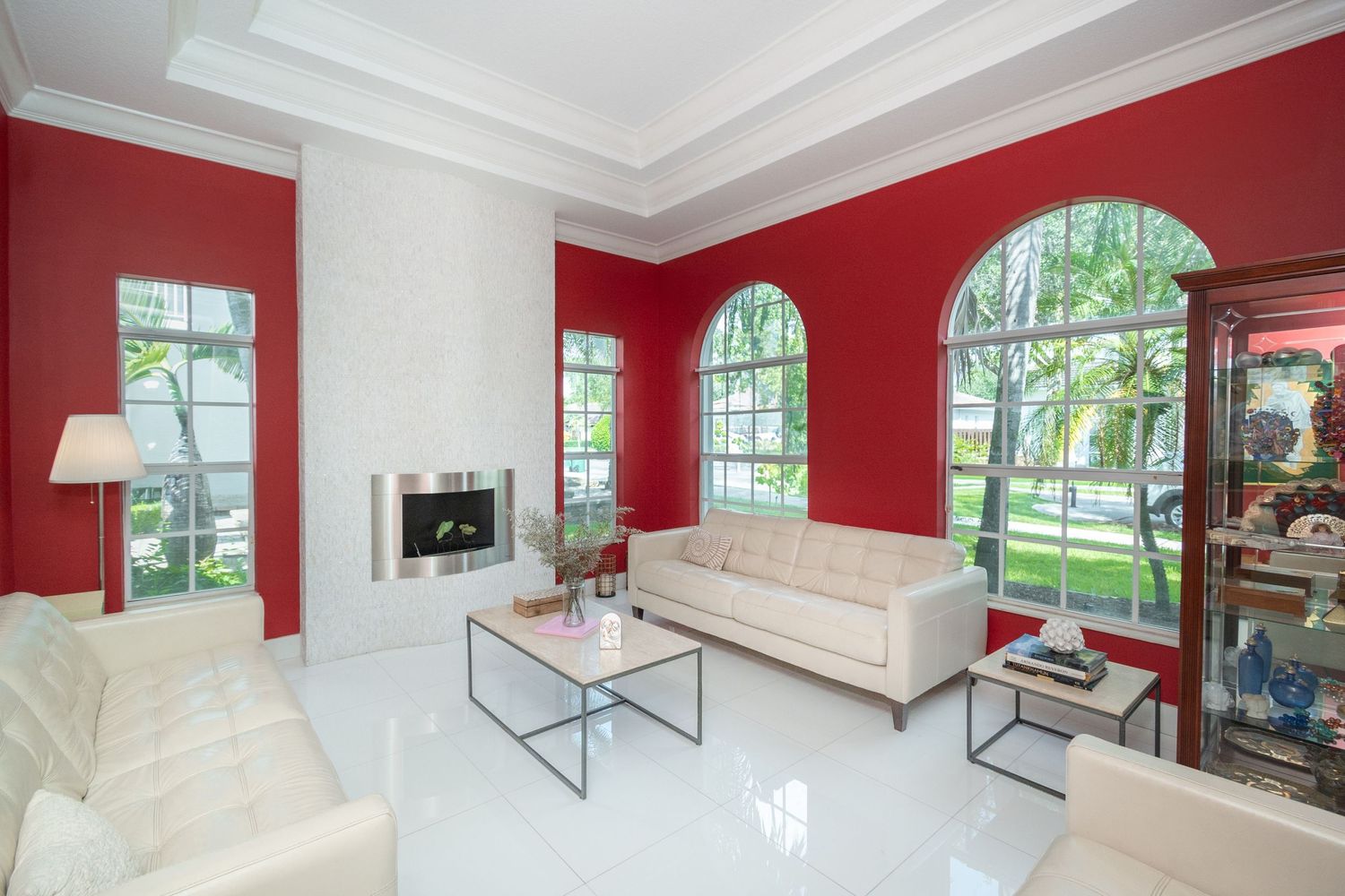 Elegant living room with red walls, white trim and arched windows.