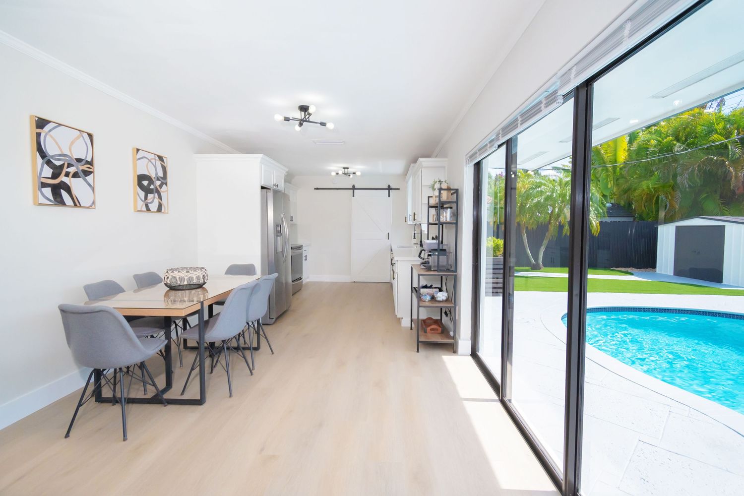 Modern dining area with sliding glass doors opening to outdoor pool area.