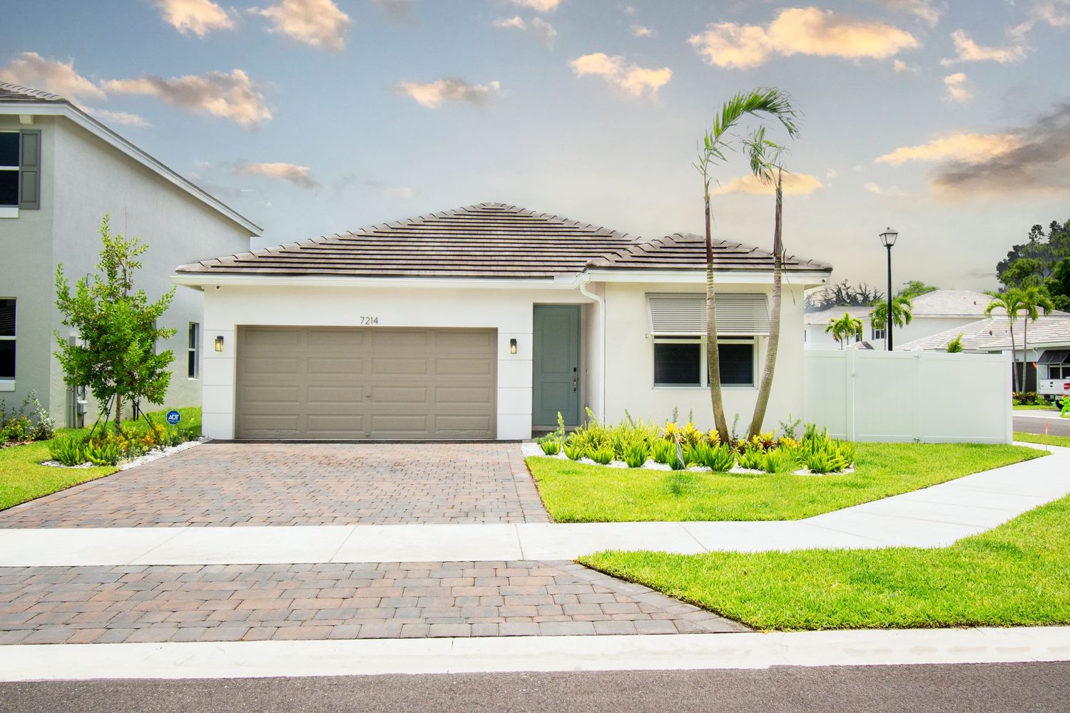 Contemporary white single-story home with garage and landscaped front yard.