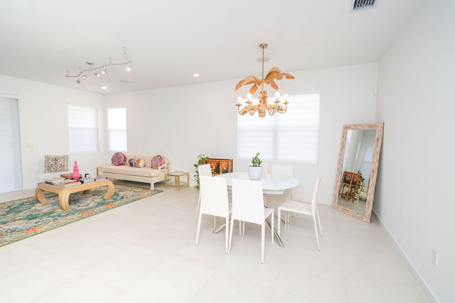Bright white dining room with modern chandelier and plush seating area.