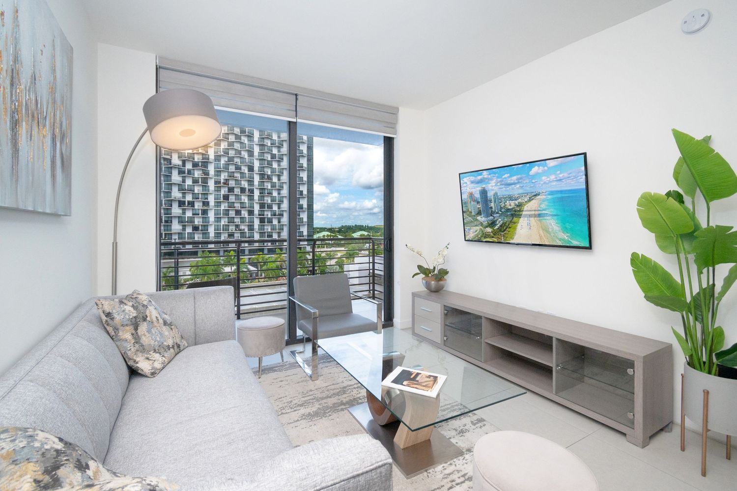 Contemporary apartment living room with balcony view and mounted TV.