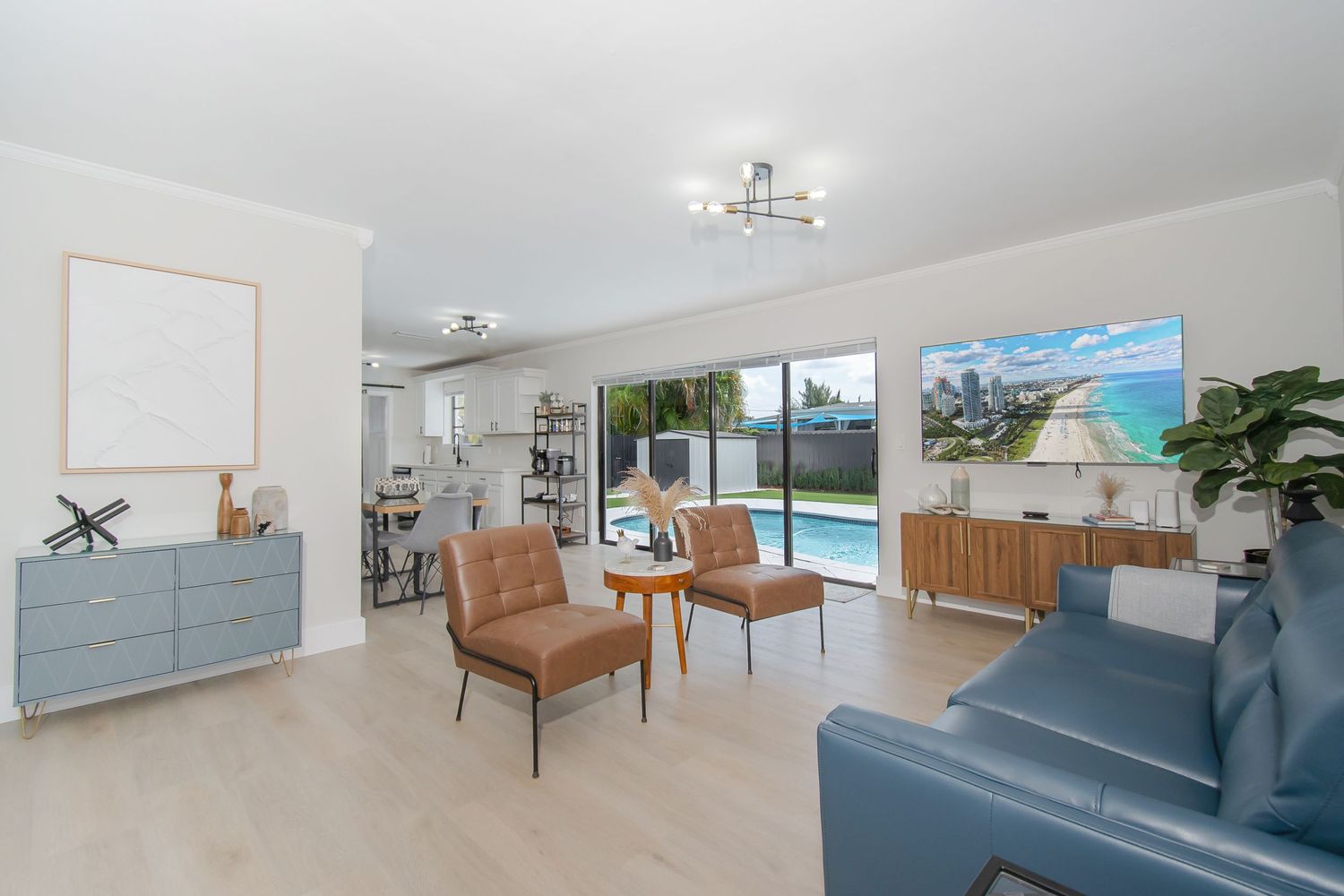Bright contemporary living room with leather chairs and ocean view artwork.