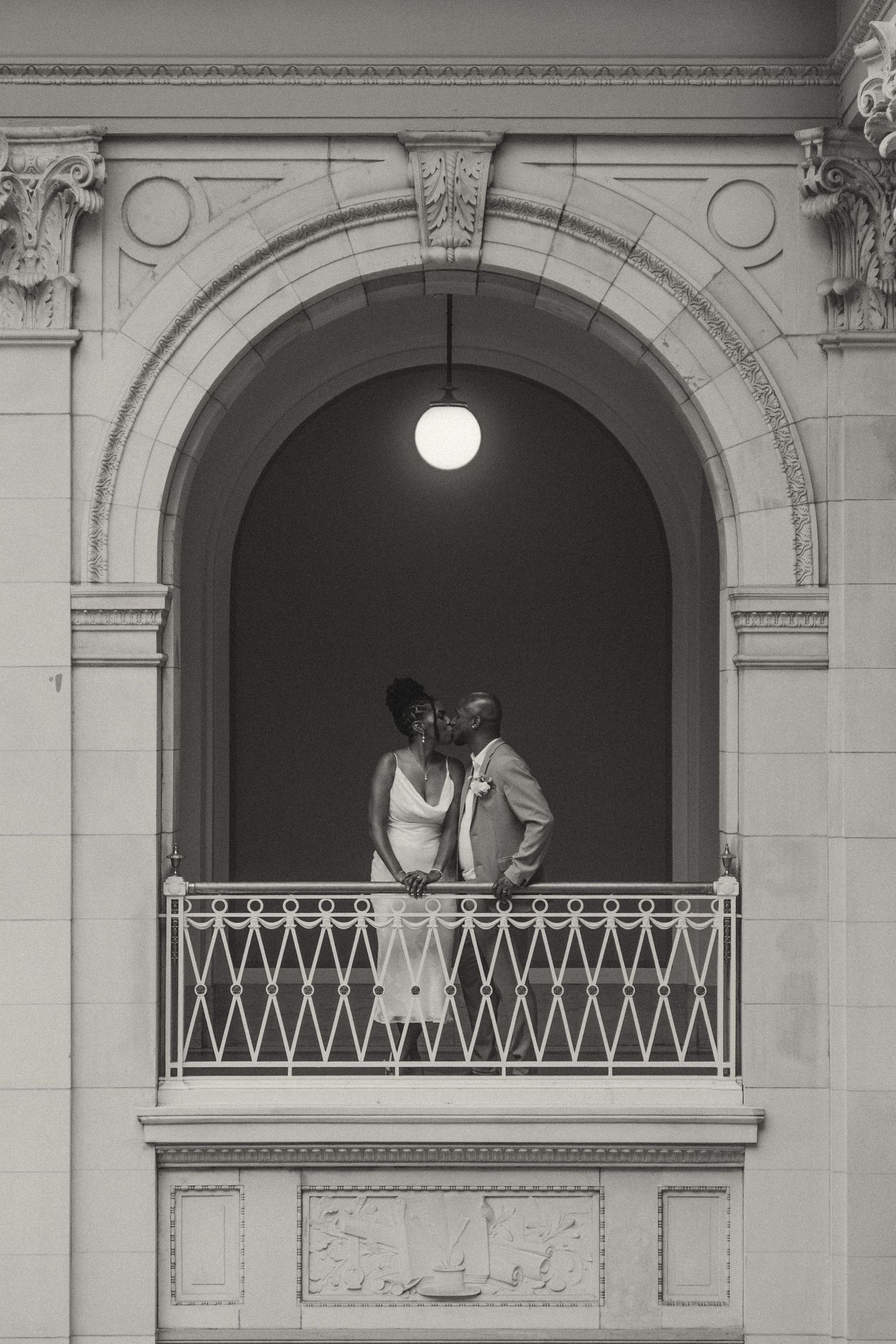 Black and white architectural photograph showing couples silhouetted in three arched balconies of a classical building.