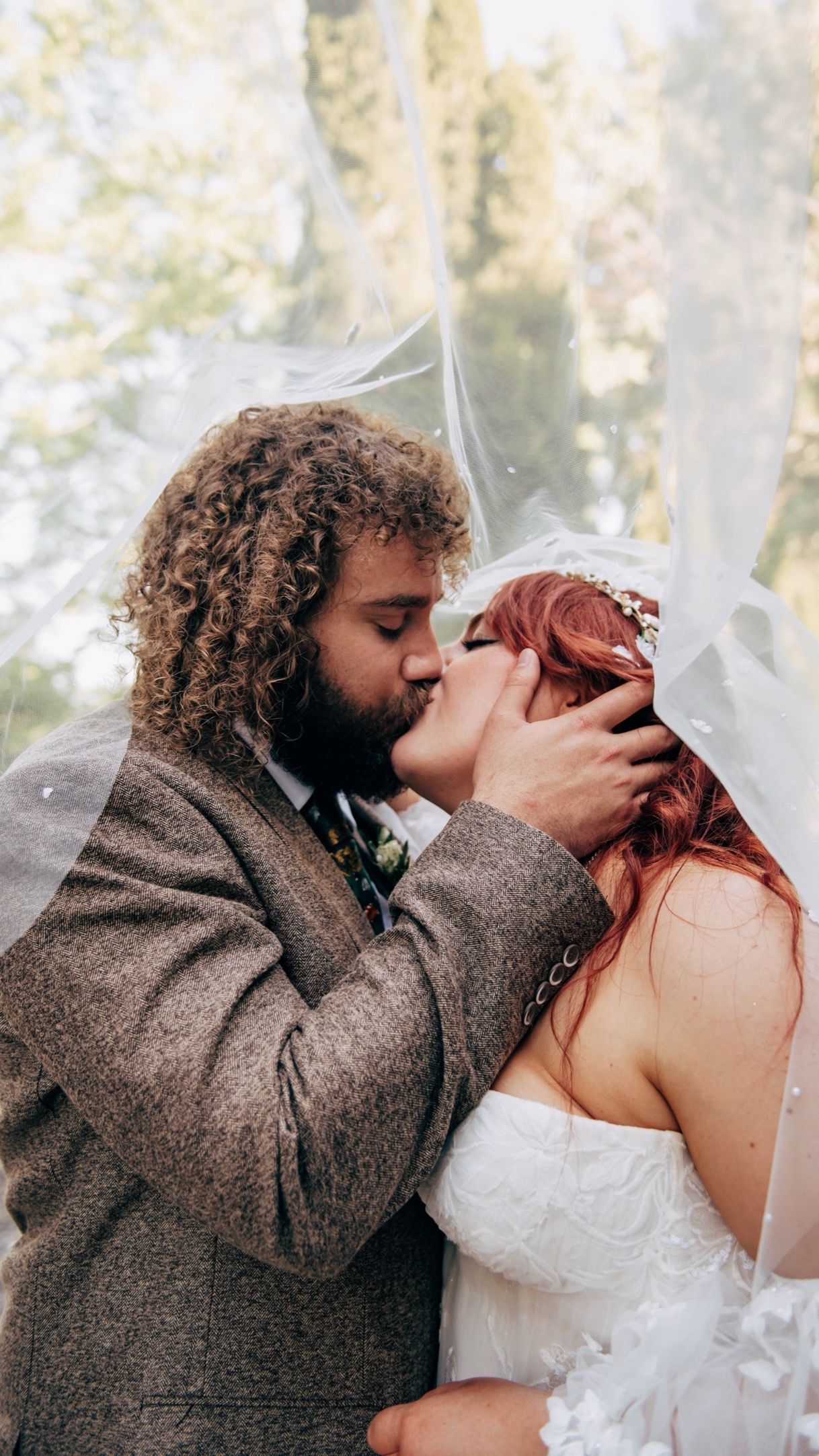 Close-up of romantic wedding kiss with groom in tweed suit and bride in white lace dress.