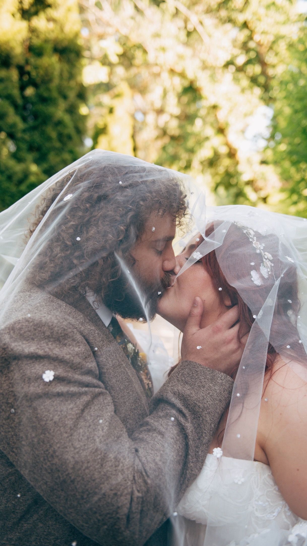 Intimate wedding moment captured as couple shares kiss under bride's veil.