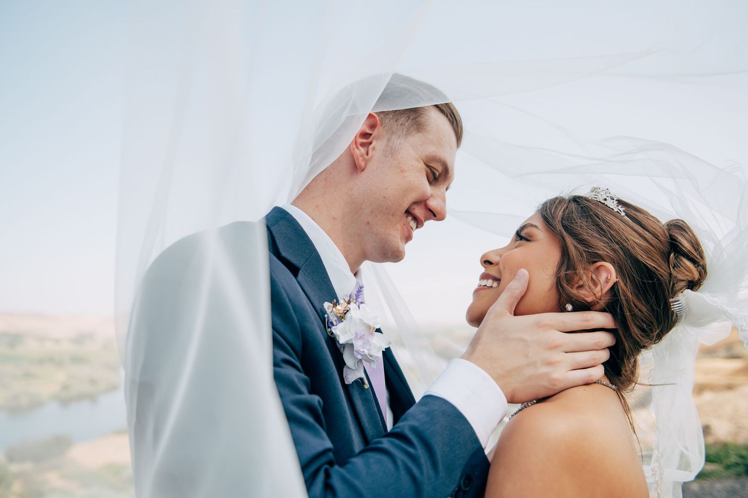 A romantic wedding couple shares an intimate moment against a scenic mountain backdrop.