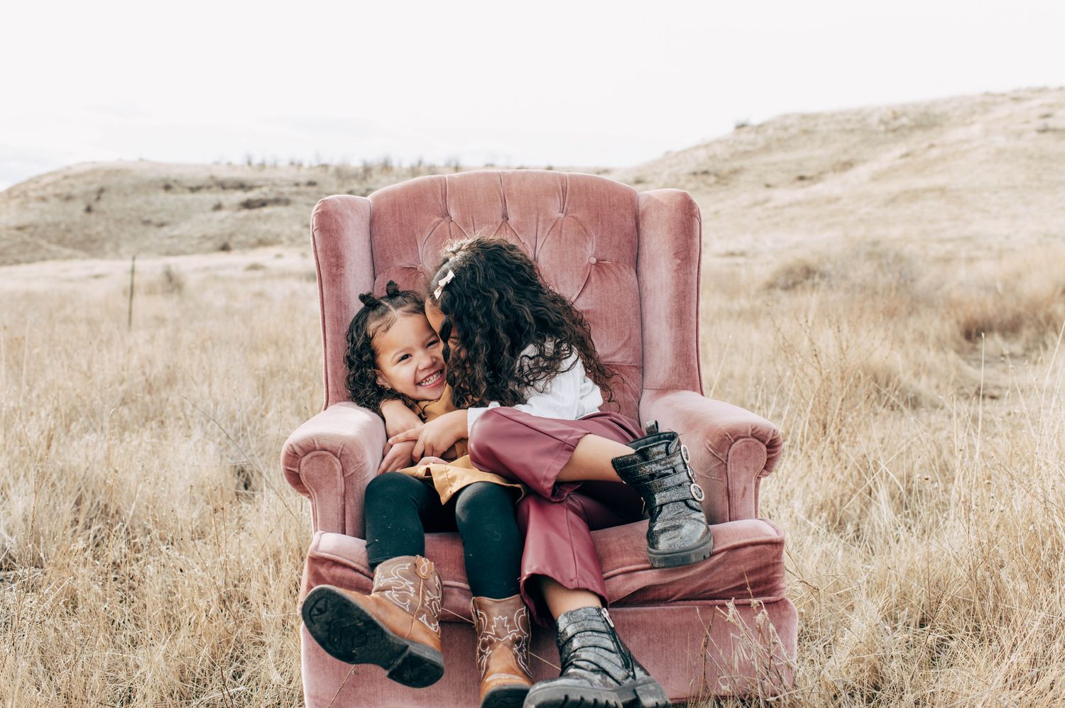 A vintage red velvet couch placed in a field of tall dried grass.