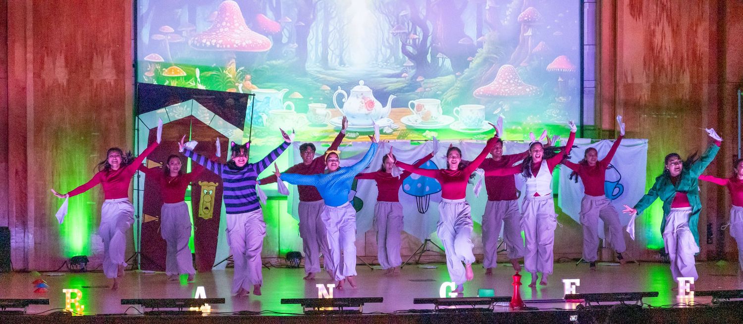 Dance performers create dynamic silhouettes against colorful stage lighting during an energetic performance.