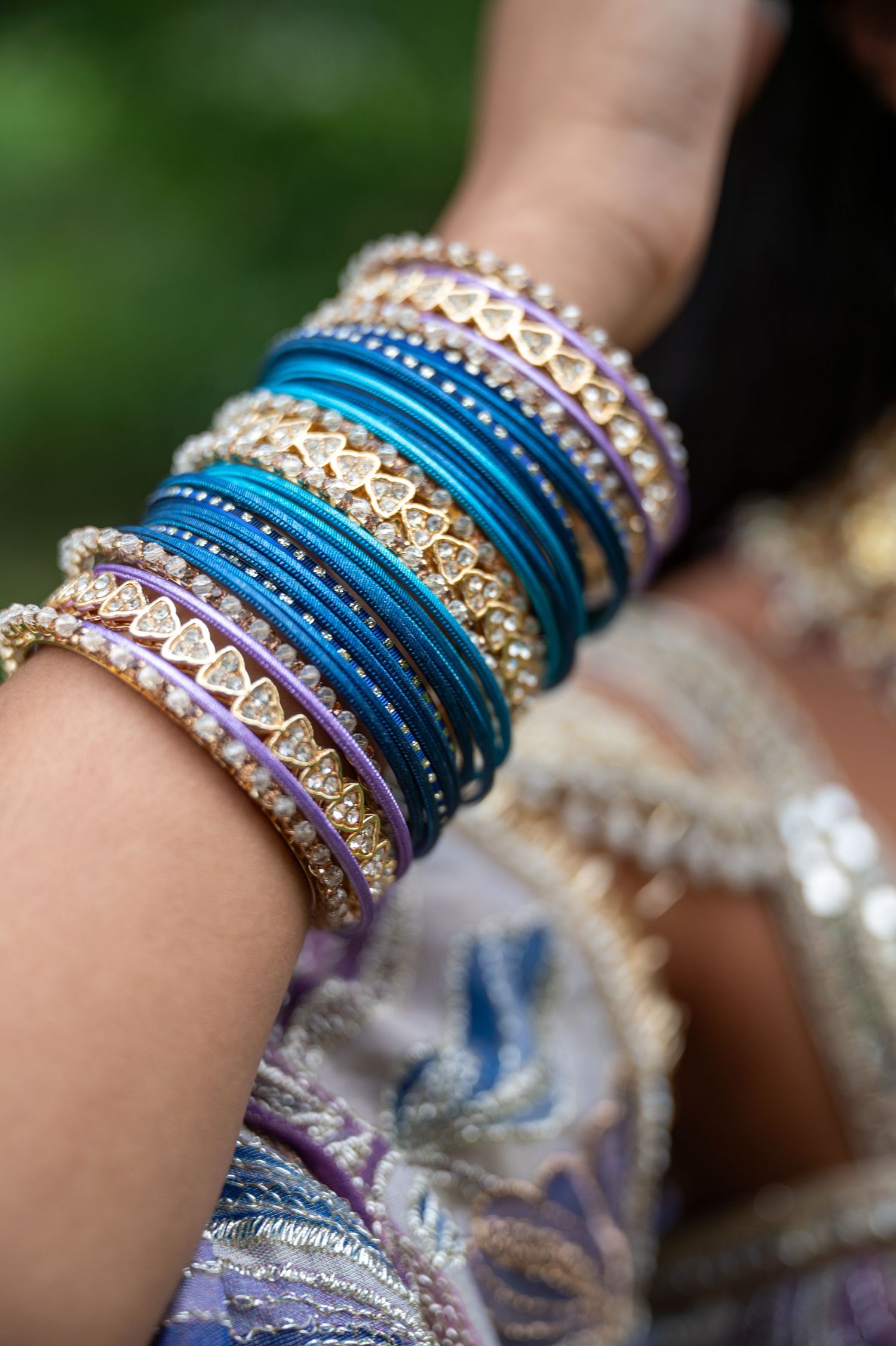 Colorful bangles and bracelets adorned with crystals and patterns in blue and purple tones.