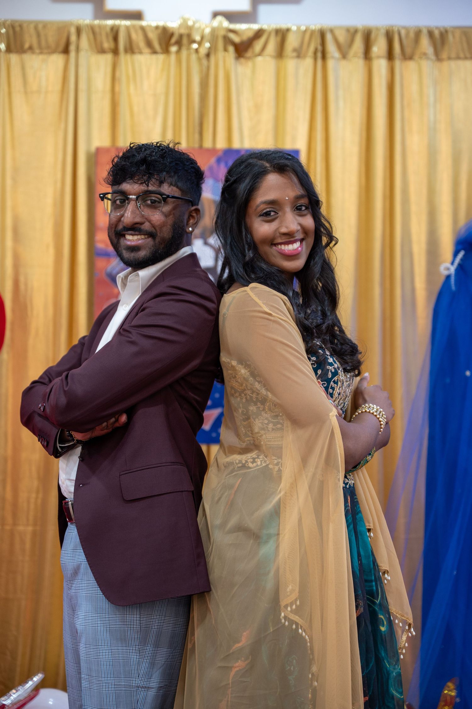 Festive gathering with people in formal attire sharing warm embraces against a gold curtain backdrop.