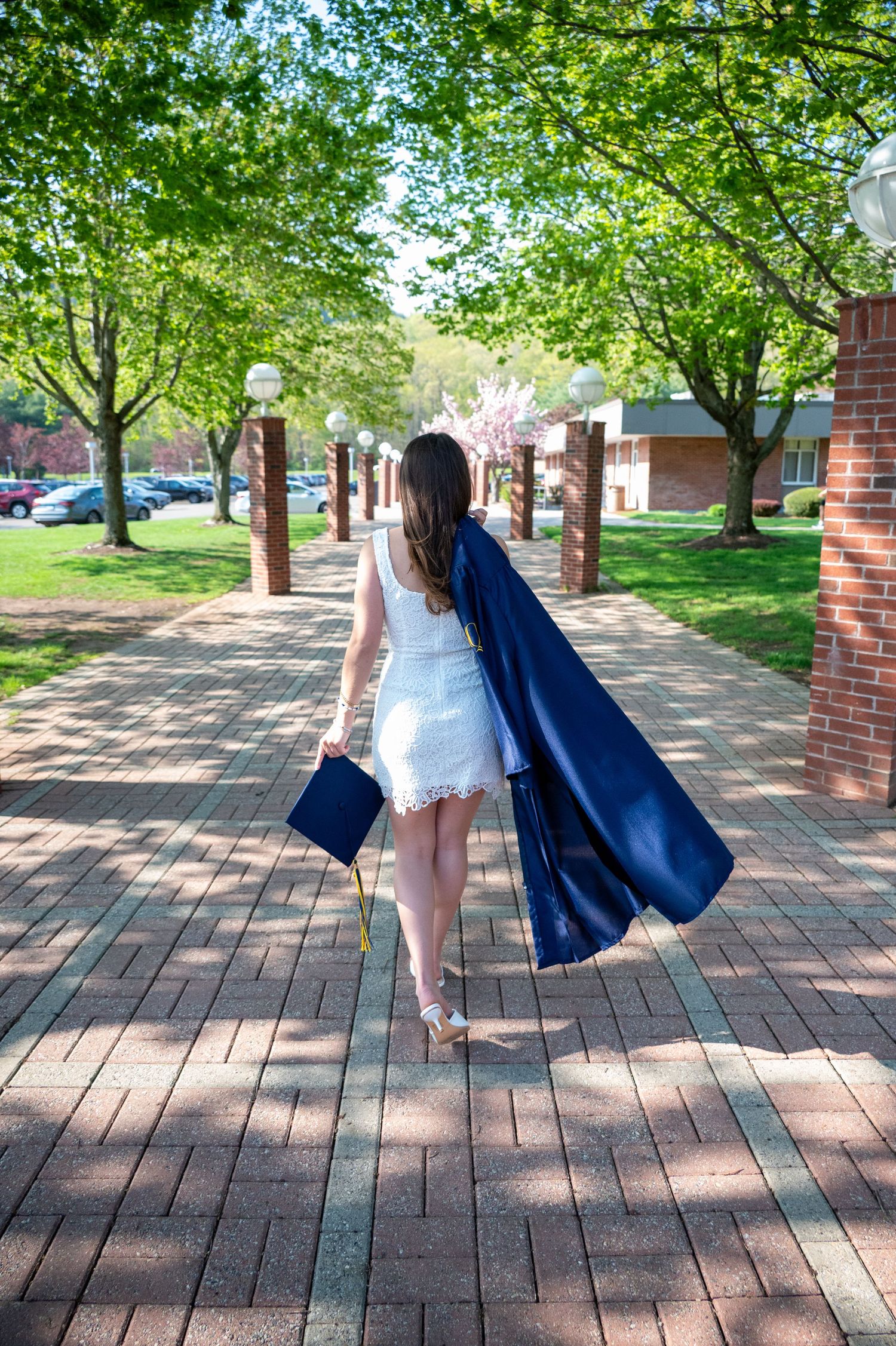 A graduation photoshoot sequence on a brick pathway surrounded by spring trees and greenery.