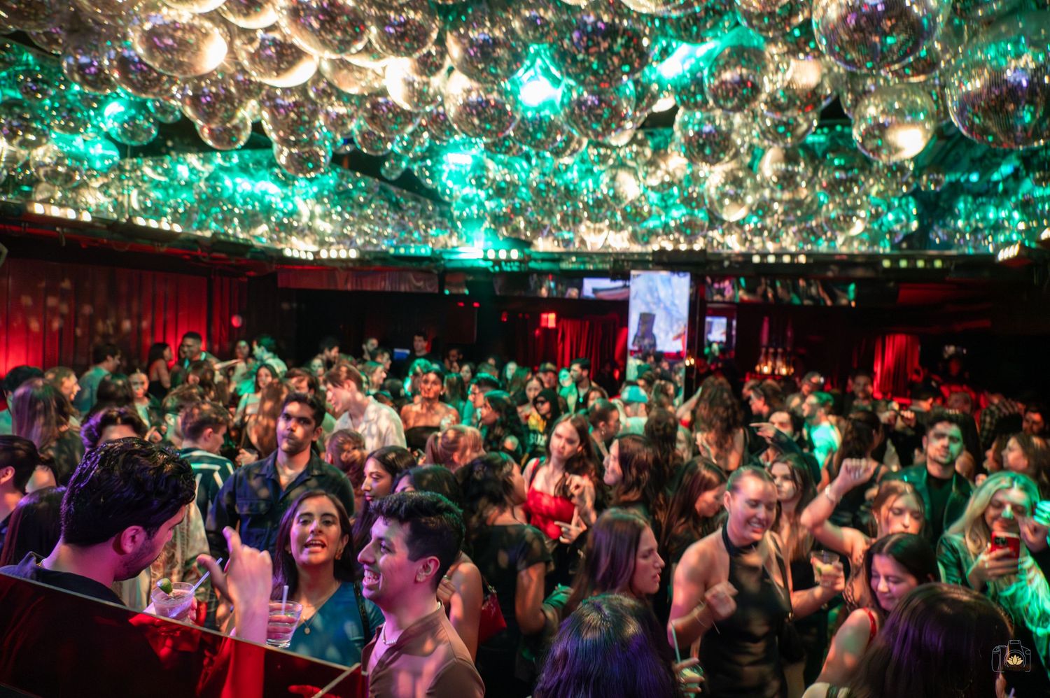 Nightclub ceiling decorated with glowing green lights and disco balls creating a festive atmosphere.