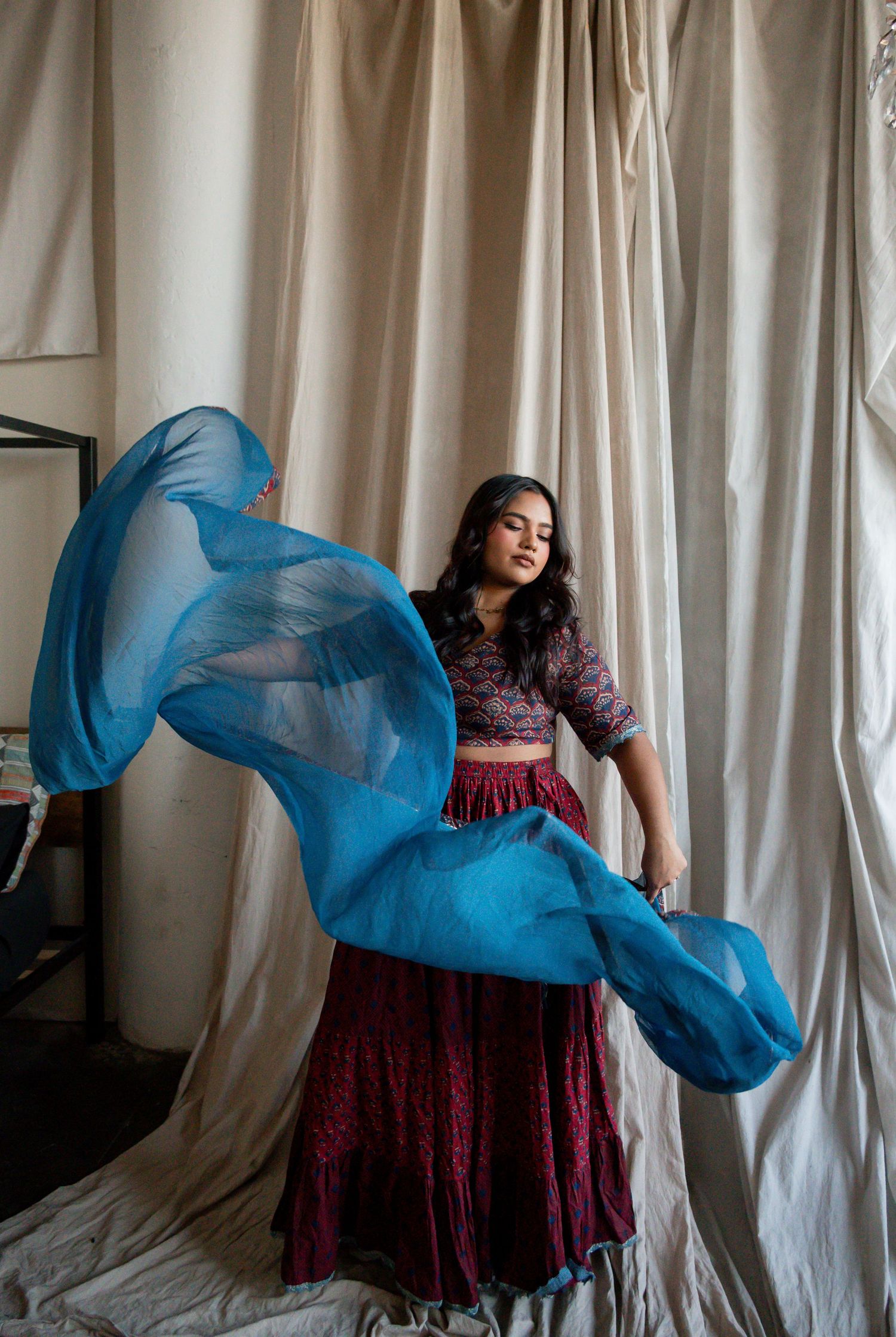Artistic fashion photo series showing flowing blue fabric movement against white curtains and burgundy dress.
