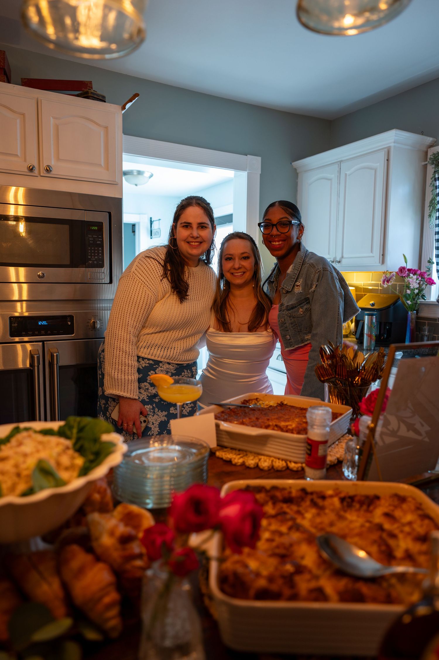 Group gathered in kitchen with prepared dishes and home-cooked meals.