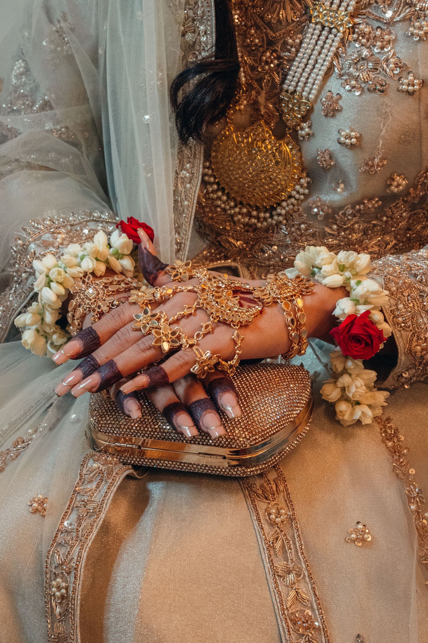 Detailed shot of bridal hands adorned with traditional Indian jewelry and nail art.