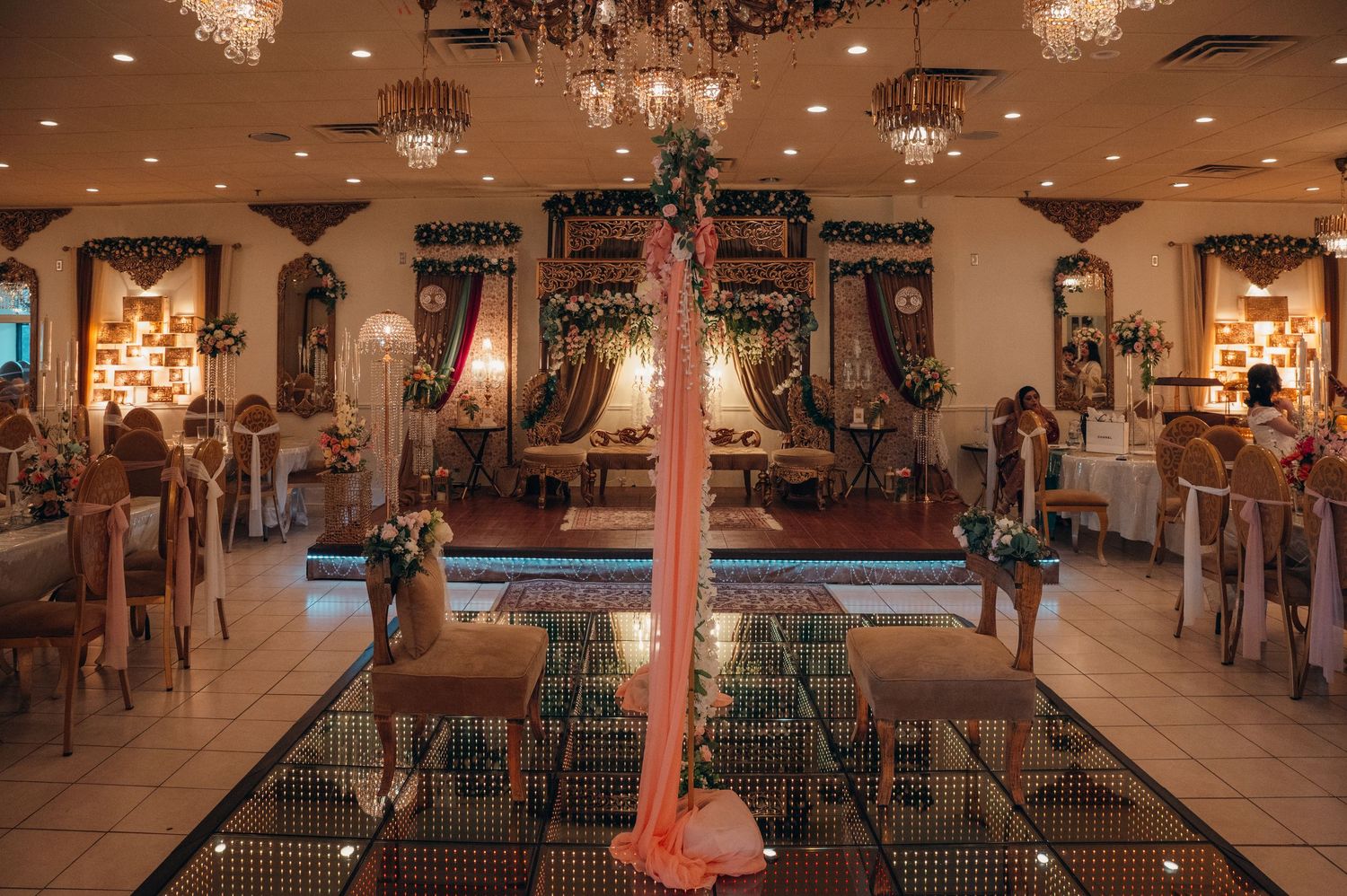 Spacious wedding reception hall with crystal chandeliers and elegant table settings.