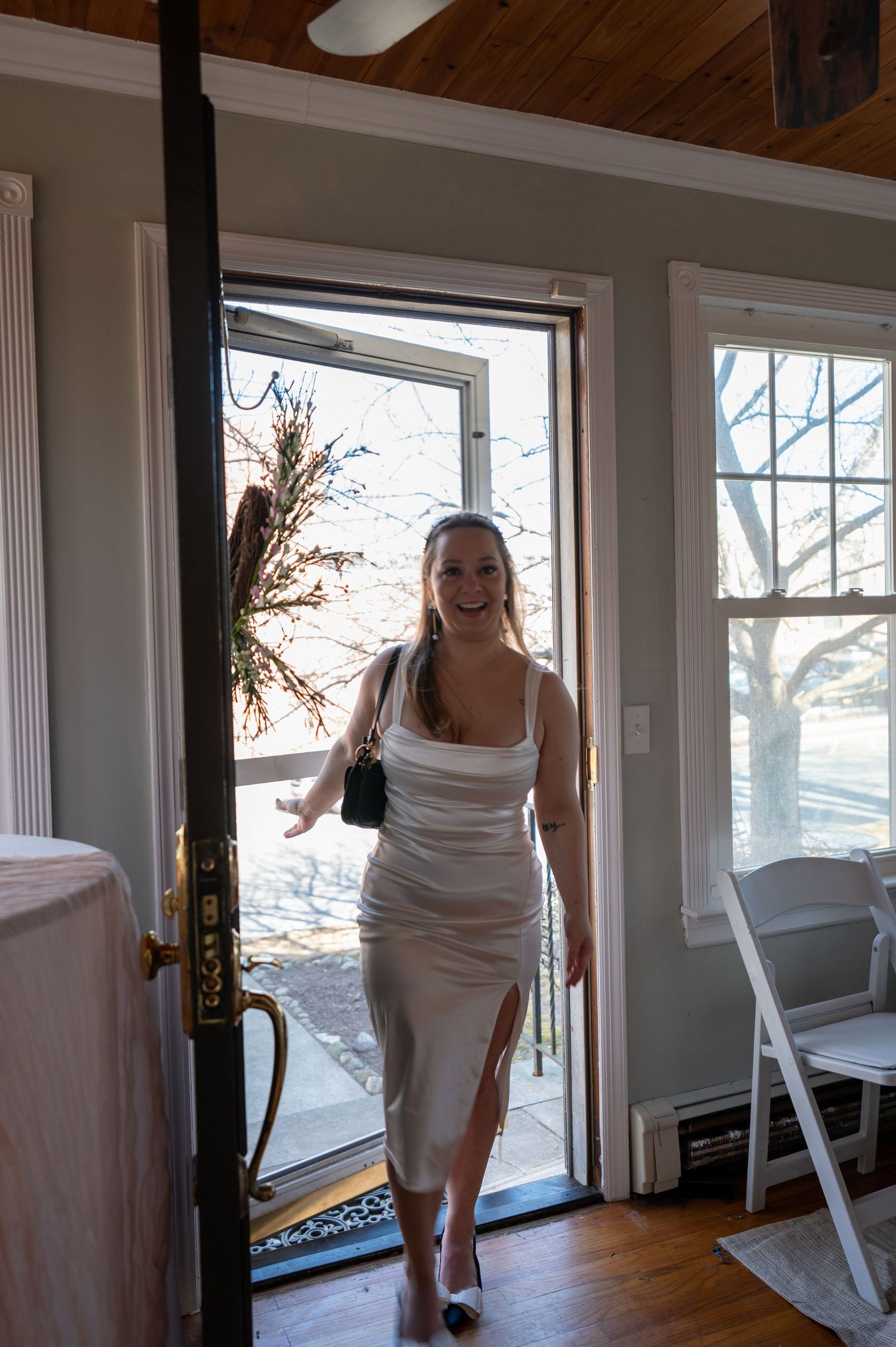 Someone in a white dress entering through a doorway at an indoor event.