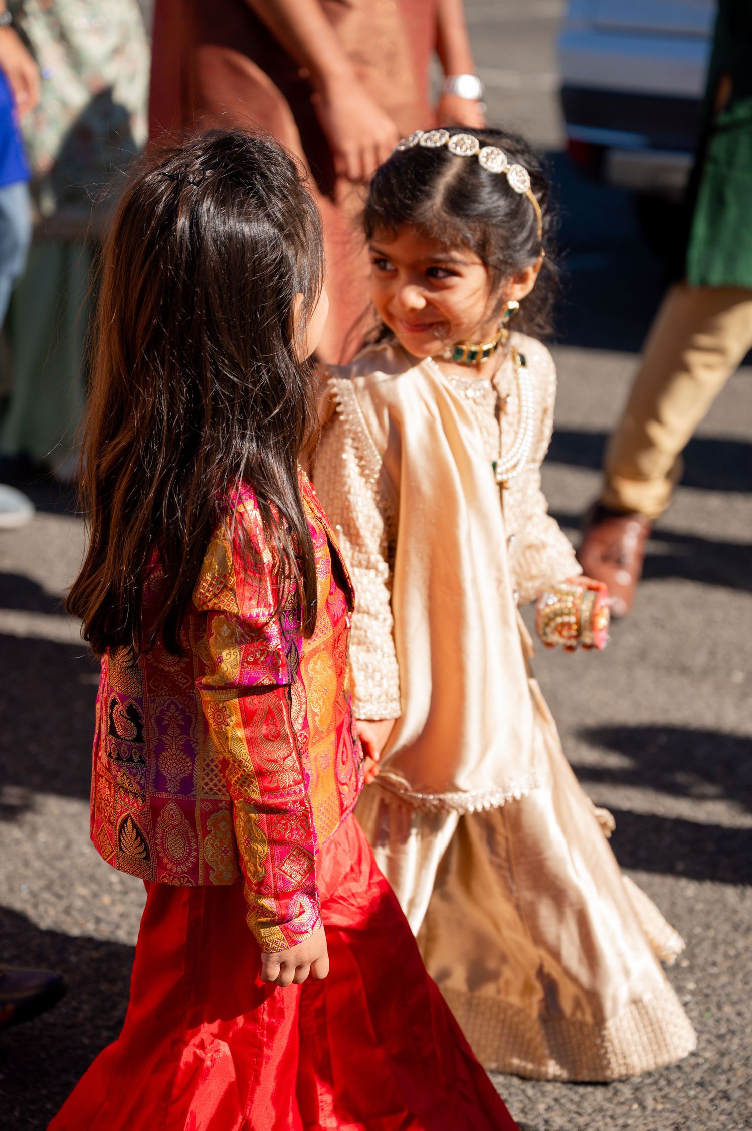 Children in colorful Indian attire walking outdoors during a celebration.