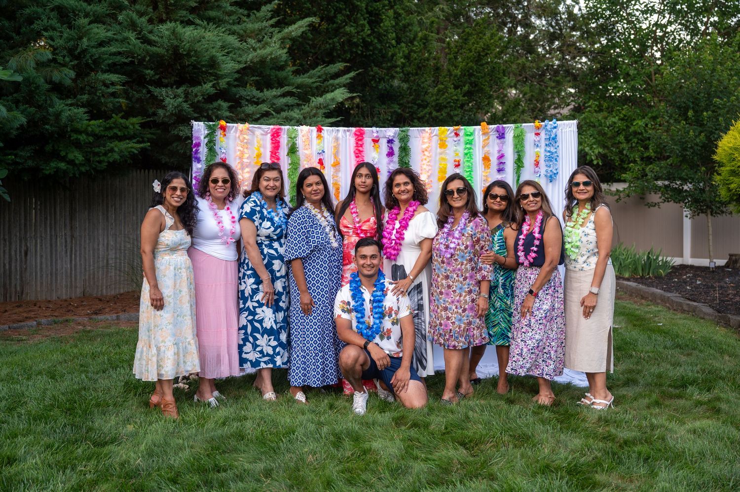 Outdoor party gathering with colorful streamers and decorations against a garden backdrop.