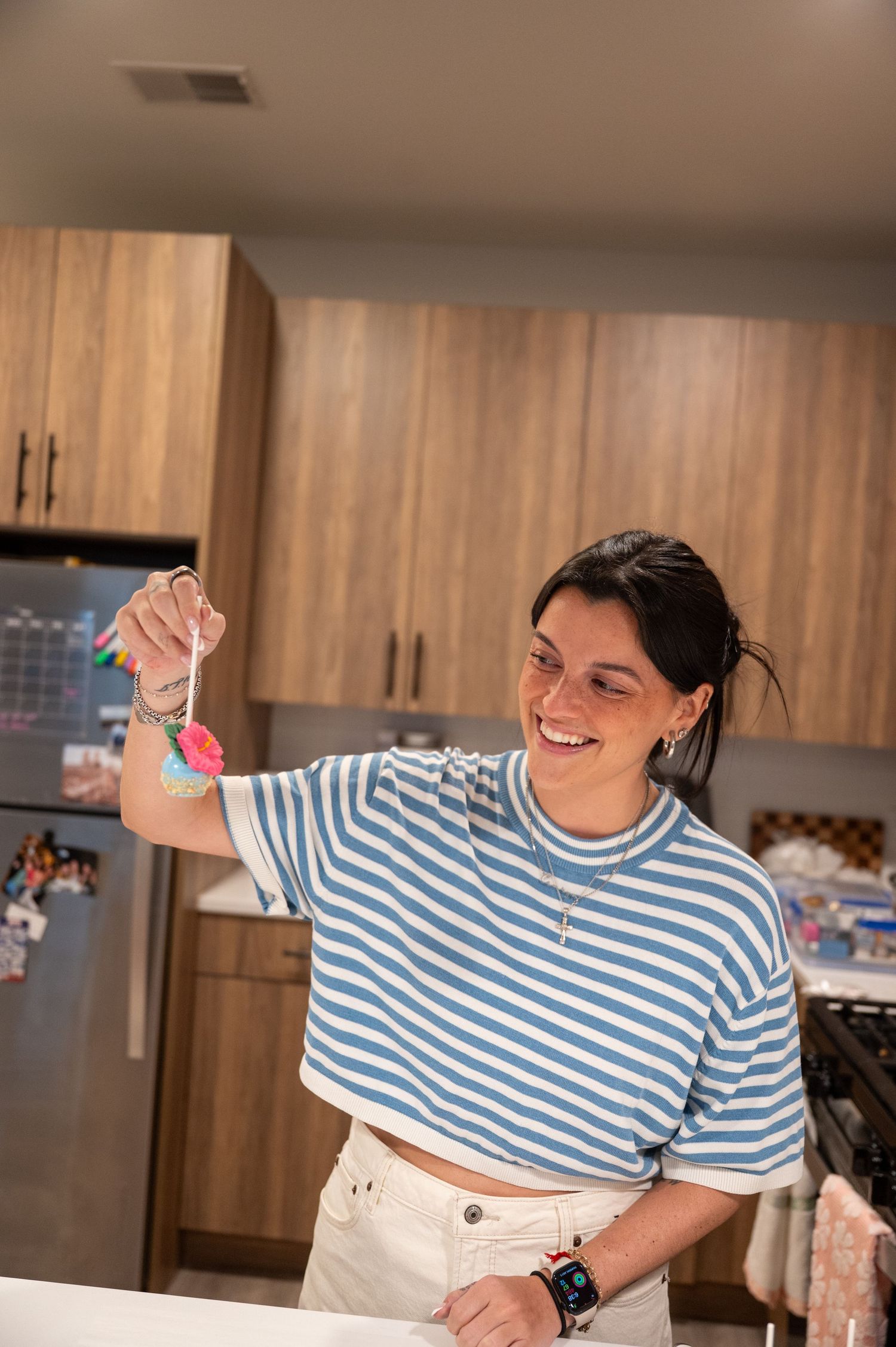 Person in striped shirt dancing joyfully in a modern kitchen setting.