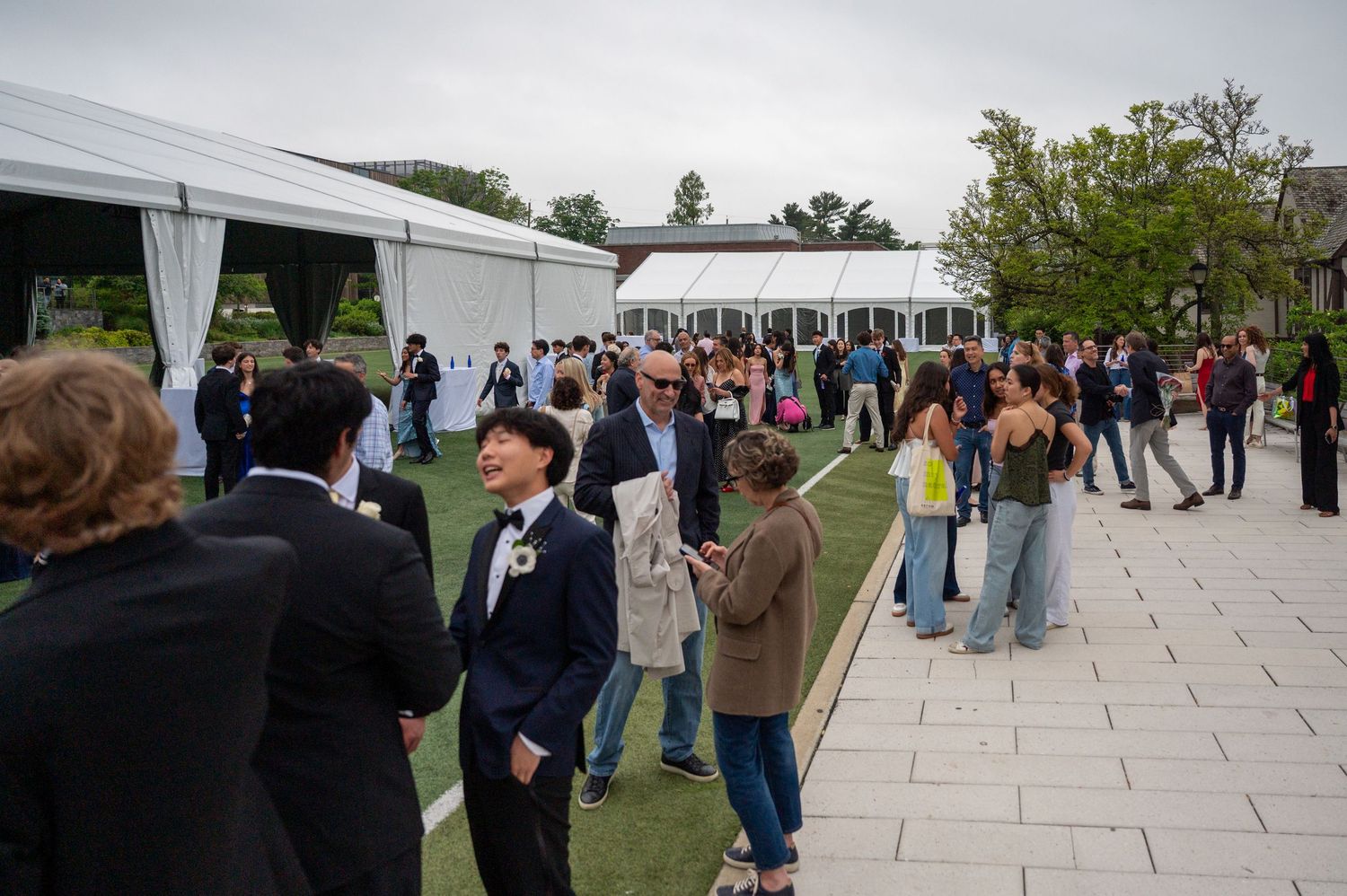 People mingling on a stone patio area outside white event tents.