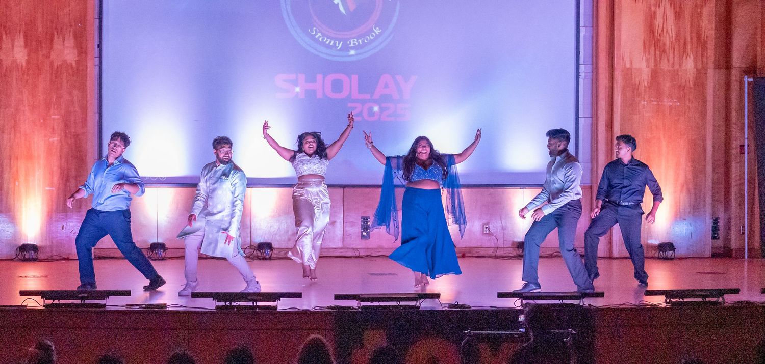 Performers on stage with purple and red lighting during a cultural show.