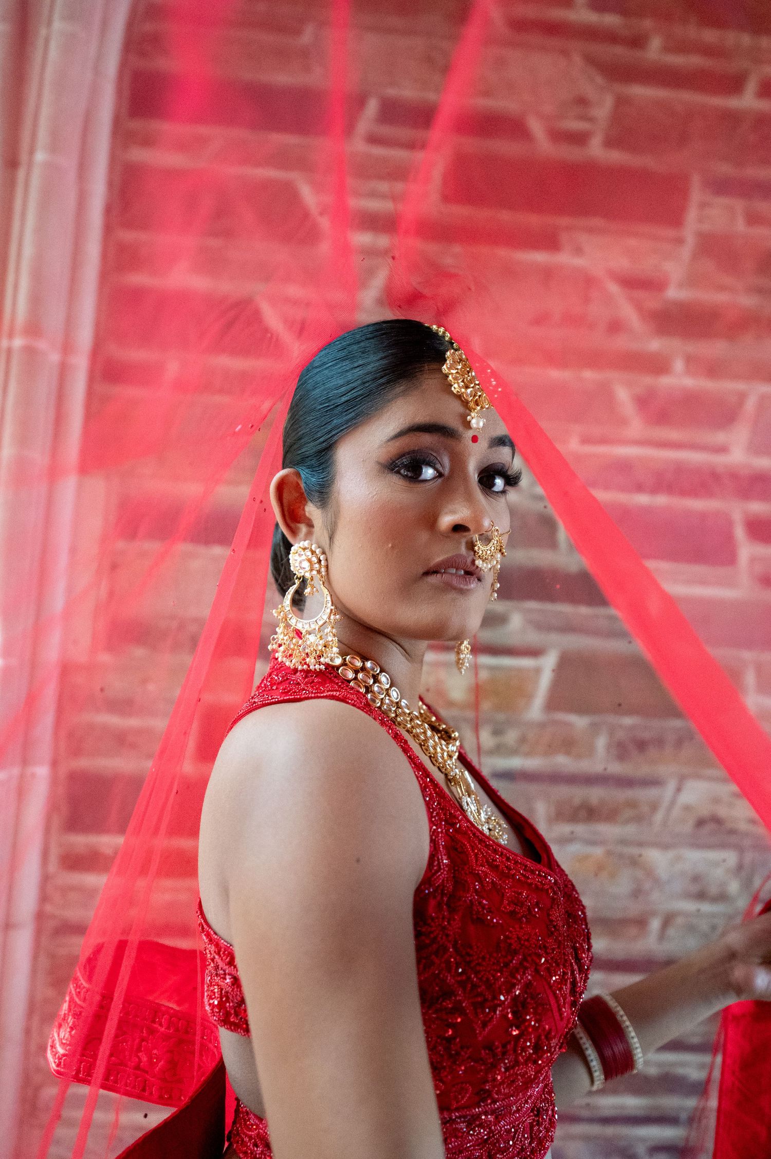 Artistic portrait sequence showing movement in a red sequined dress against a brick wall background.