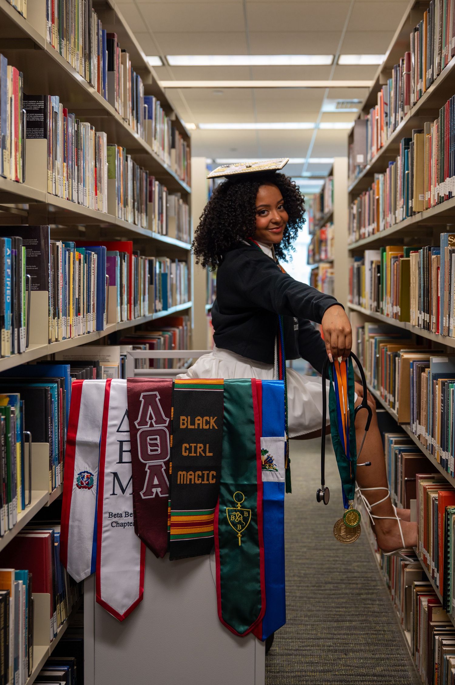 A library photoshoot showcasing academic stoles and banners displayed between bookshelves.