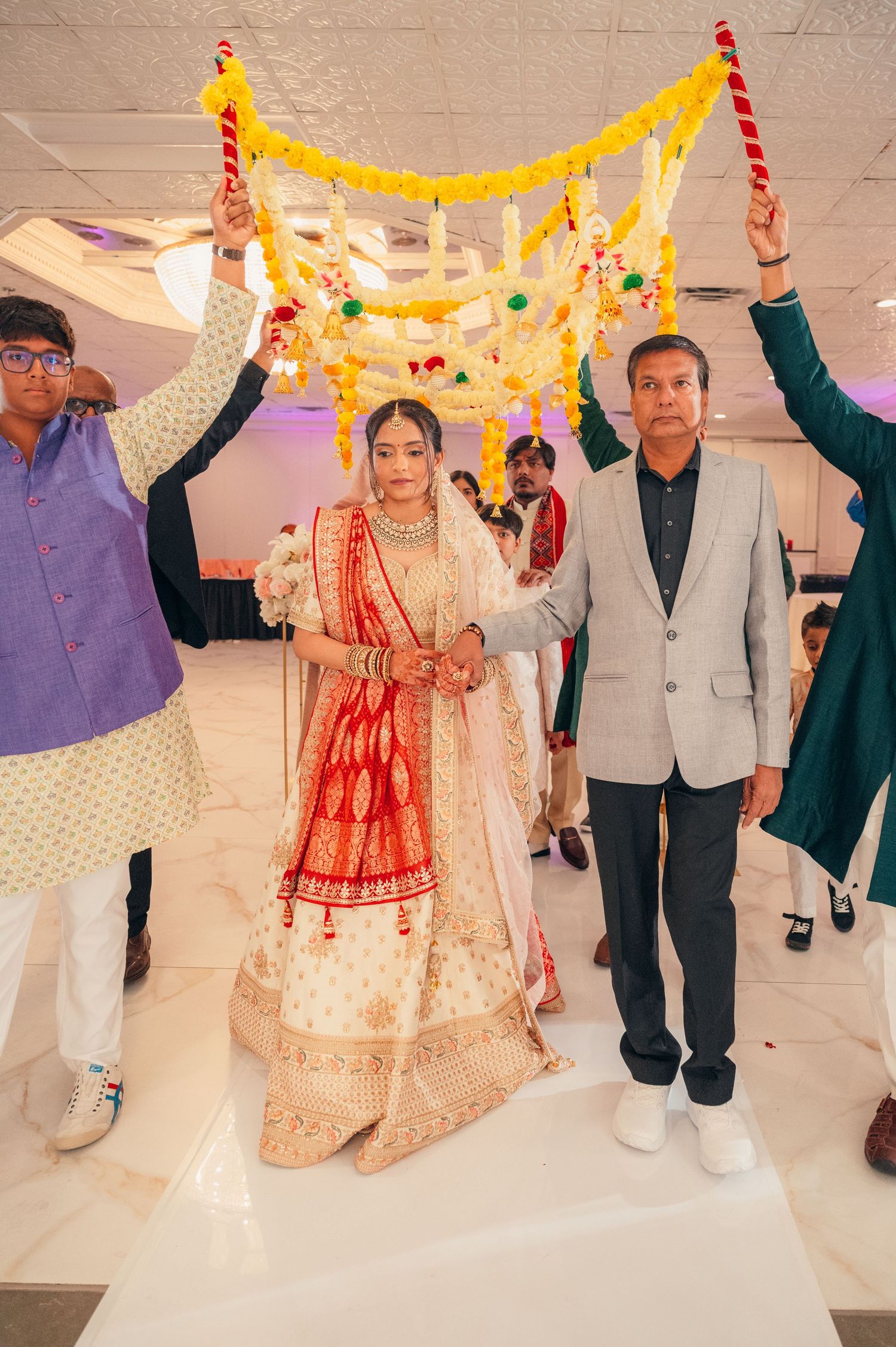 Wedding celebration with guests holding yellow decorative fabric overhead during ceremony.