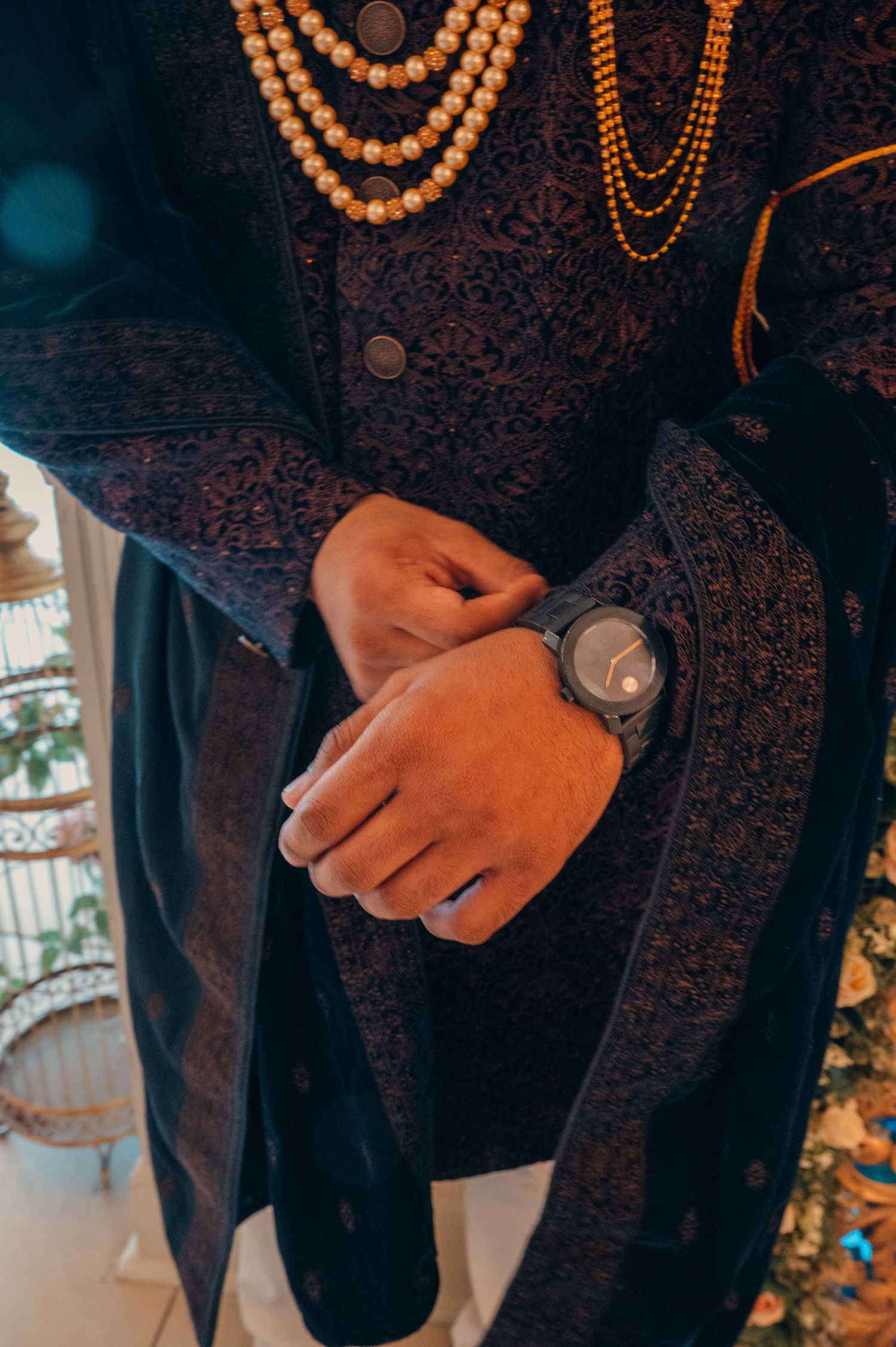 Traditional groom's attire featuring detailed embroidery and beaded necklaces.