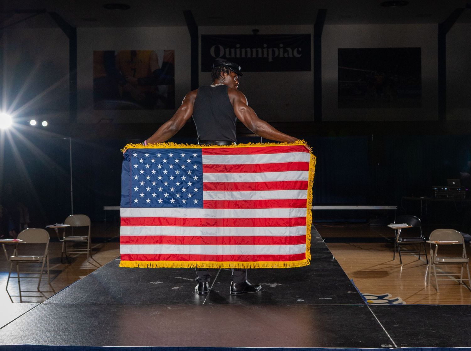 American flags are displayed on a dark stage with dramatic spotlighting.