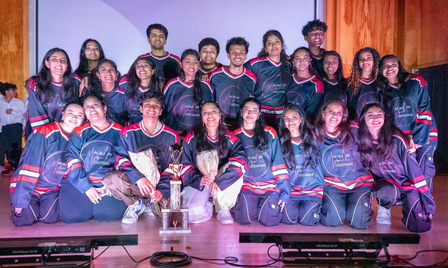Group photo of performers in matching outfits after their stage show.