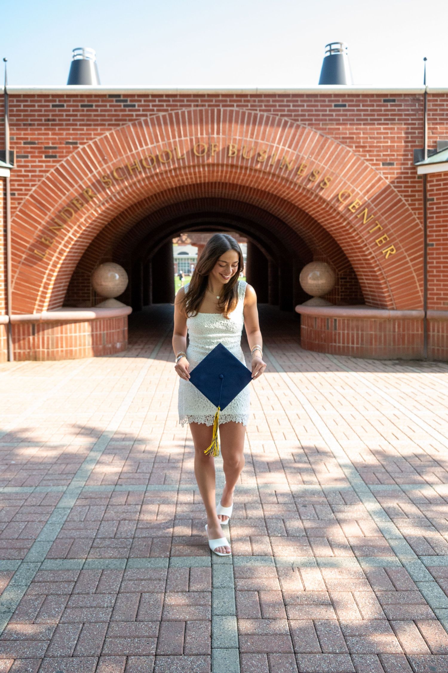 Graduate spins joyfully under brick archways on campus.