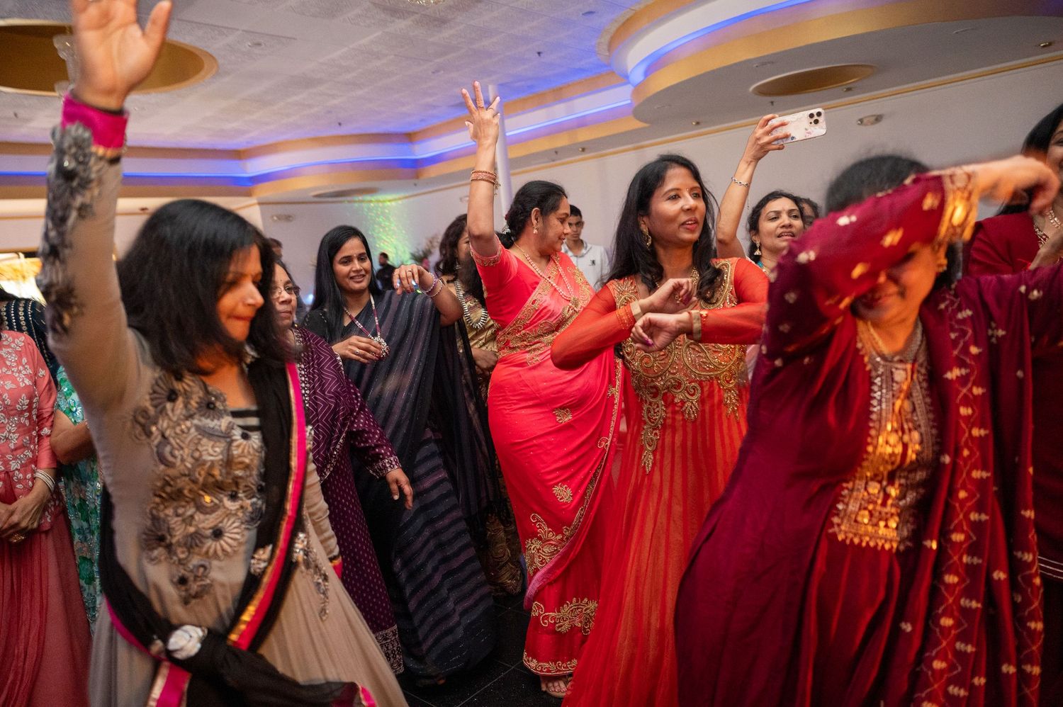 Group of people in colorful traditional attire dancing together at a celebration.